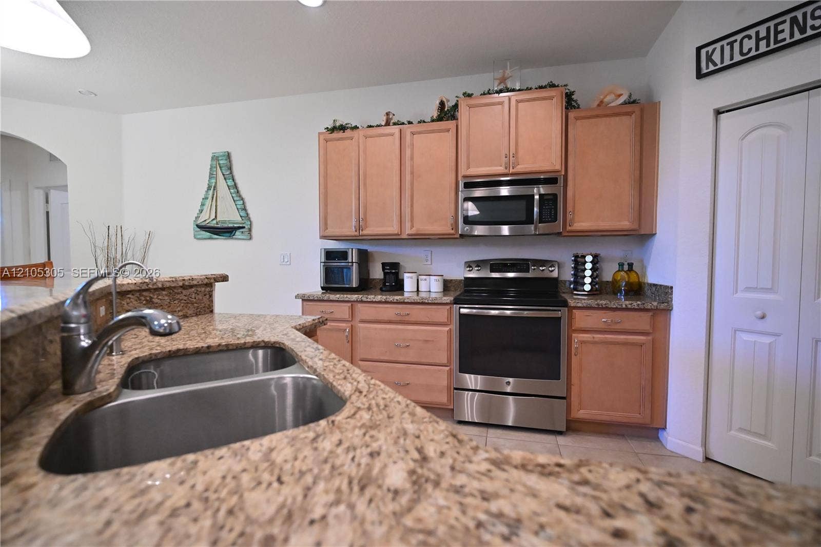 Kitchen featuring a dual basin sink, stainless steel appliances, granite-style countertops, and wood-finish cabinetry