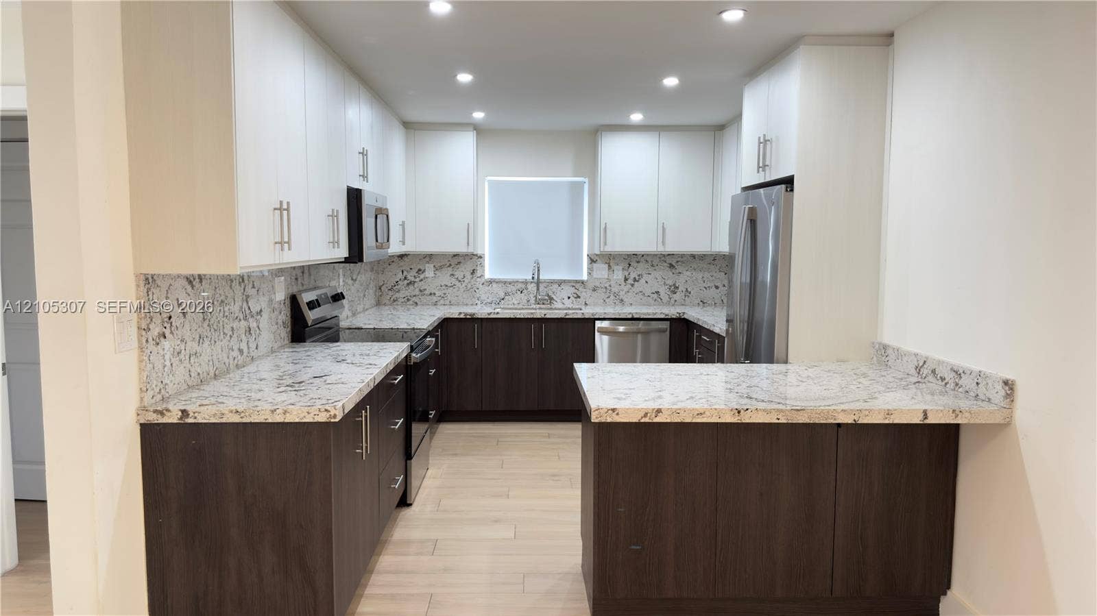 Kitchen featuring two-tone cabinetry, stone-finish countertops, stainless steel appliances, recessed ceiling lighting, and wood-finish flooring
