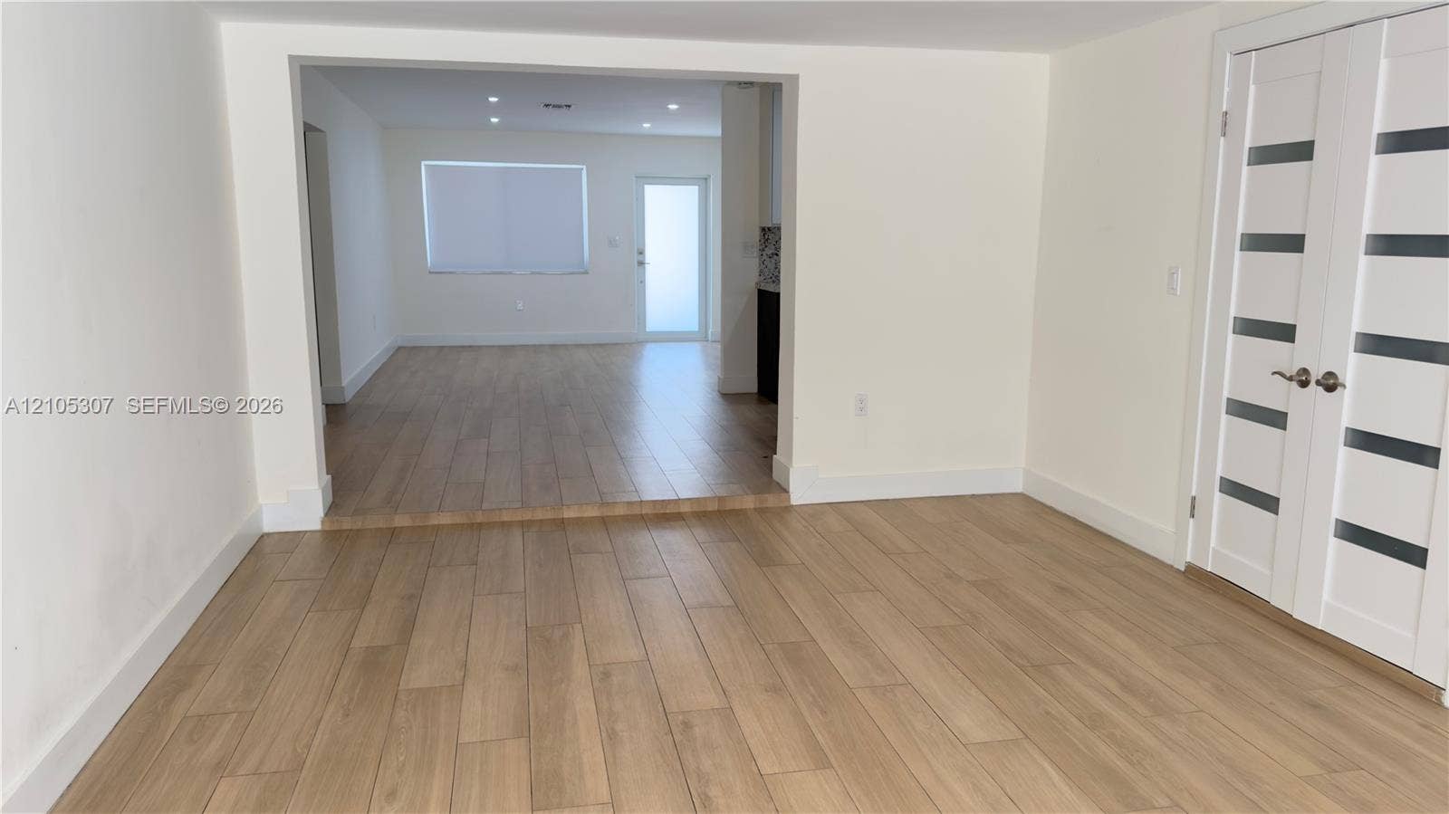 Wood-finish flooring throughout, recessed ceiling lighting, and double-door entry featuring glass horizontal panels