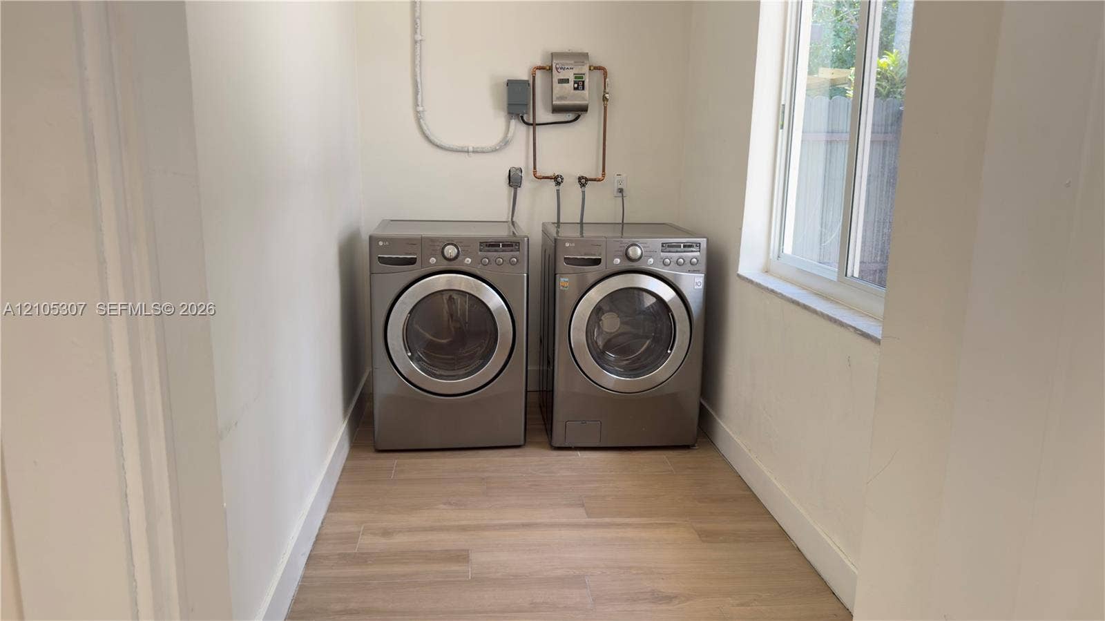 Dedicated laundry space featuring wood-finish flooring and a single-hung window