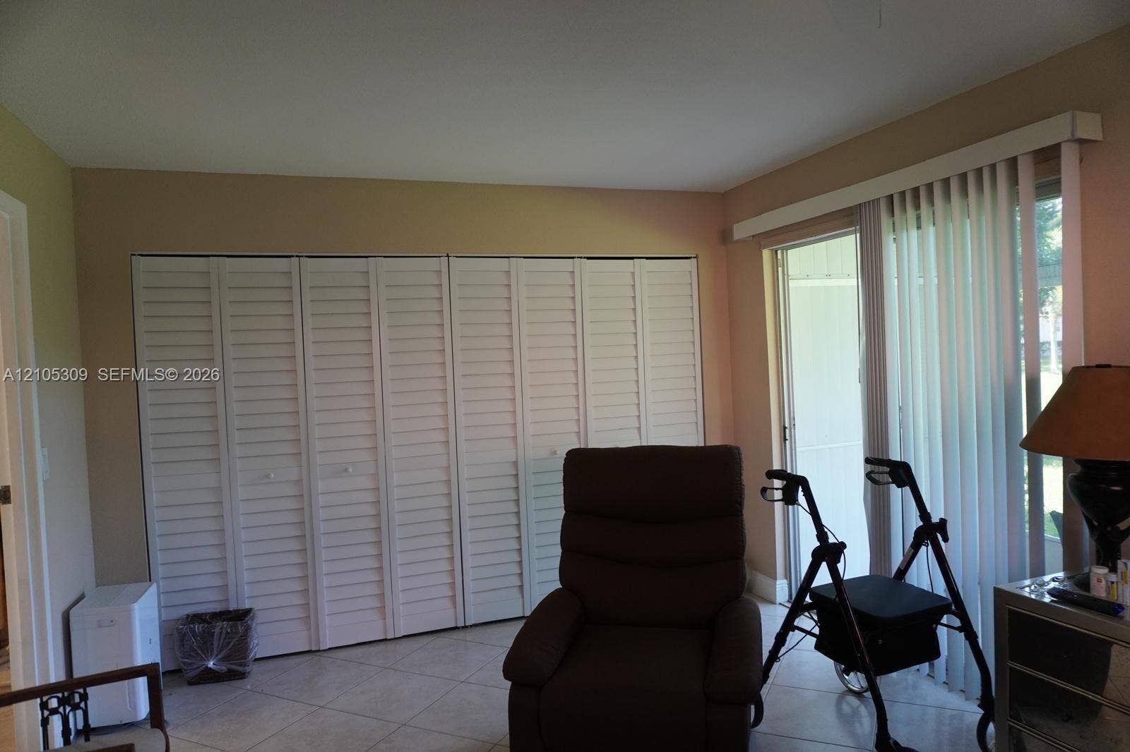 542 Saxony L, #542, Delray Beach, FL 33446 Full-wall louvered closet doors, neutral wall finish, ceramic tile flooring, and vertical blinds covering the sliding glass door