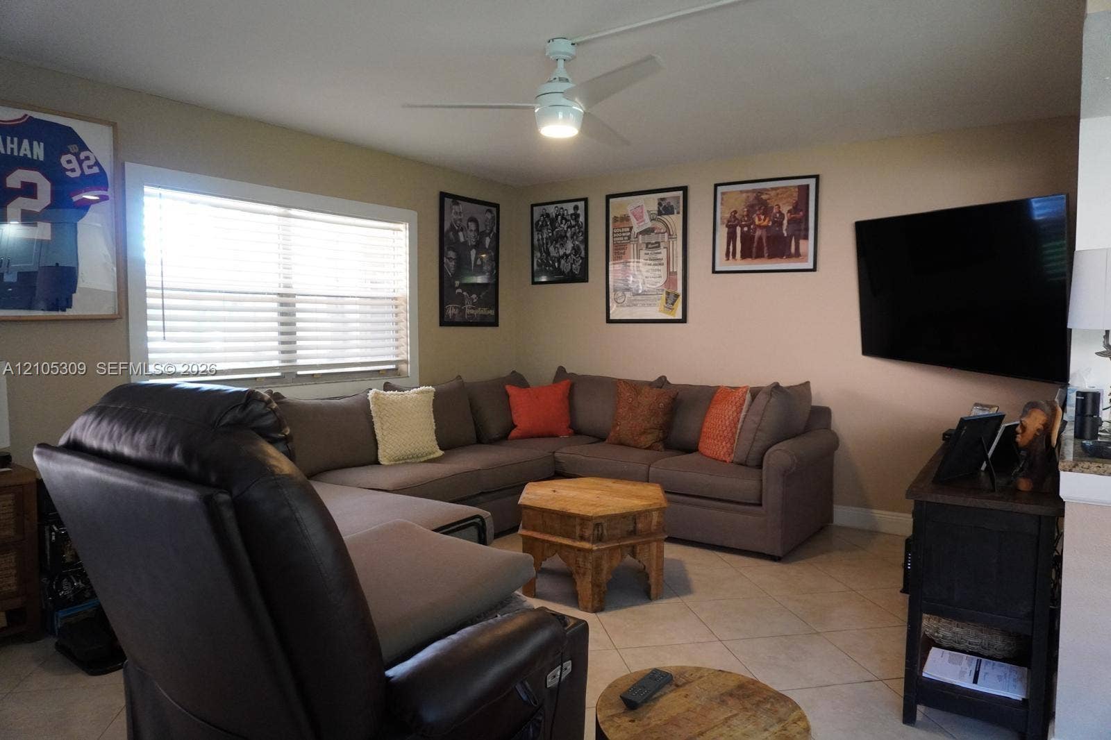542 Saxony L, #542, Delray Beach, FL 33446 Neutral interior featuring light-toned tile flooring, a dual-function ceiling fan with integrated lighting, and a large picture window with horizontal blinds