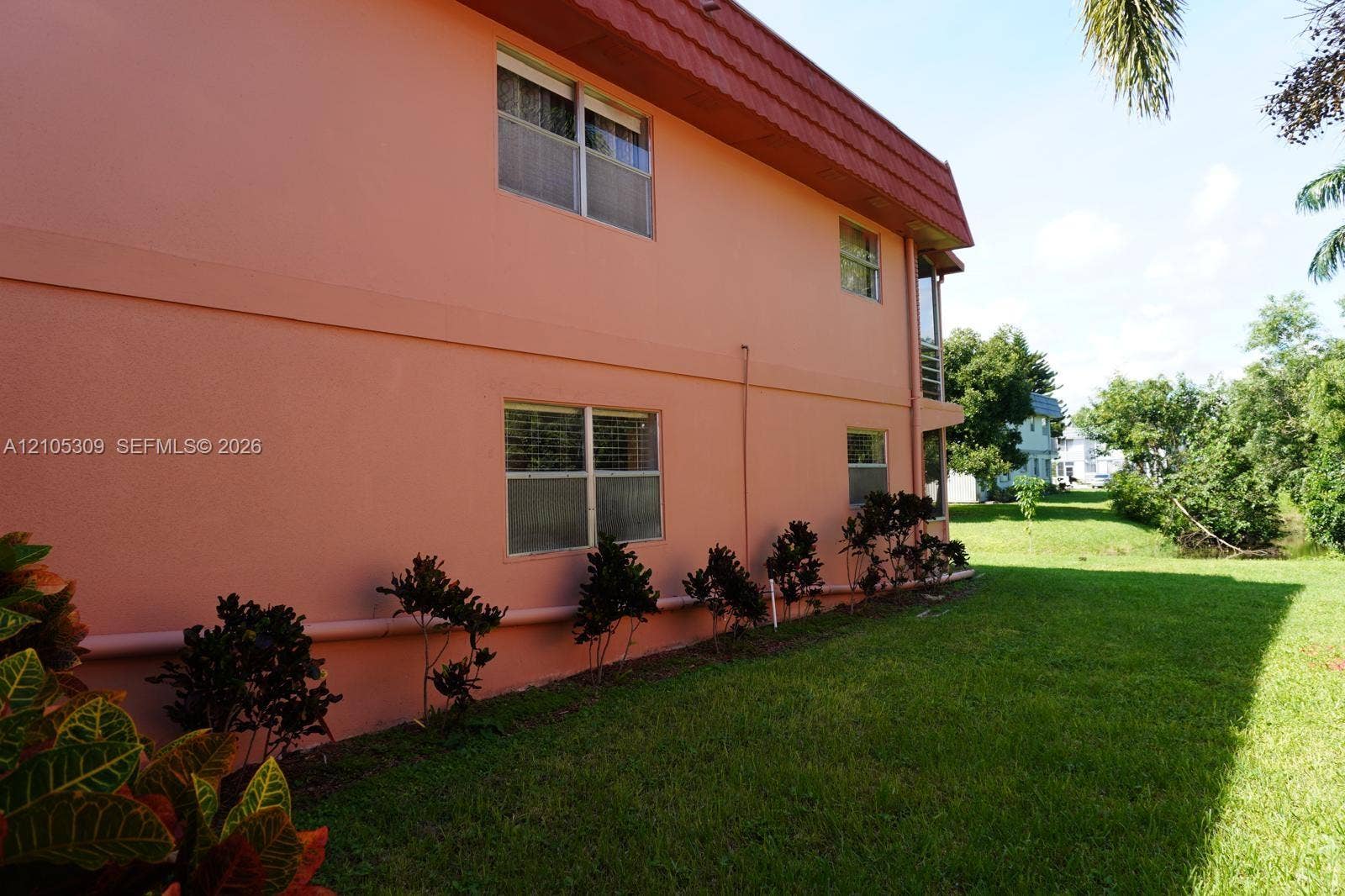 542 Saxony L, #542, Delray Beach, FL 33446 Two-story exterior featuring smooth stucco siding, a mansard roofline, multi-pane windows, and manicured perimeter landscaping