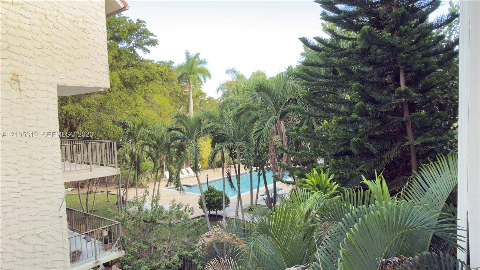 6900 N Kendall Drive, #A304, Pinecrest, Pinecrest, FL 33156 Outdoor space featuring an in-ground swimming pool, multi-level metal-railed balconies, and mature landscaping including palm and evergreen trees