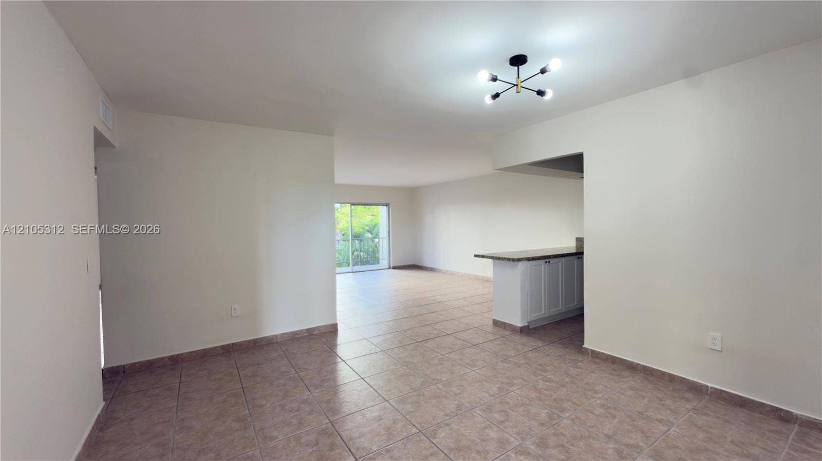 6900 N Kendall Drive, #A304, Pinecrest, Pinecrest, FL 33156 Neutral-toned interior featuring ceramic tile flooring, a multi-arm modern ceiling fixture, and a built-in kitchen peninsula with stone-finish countertop