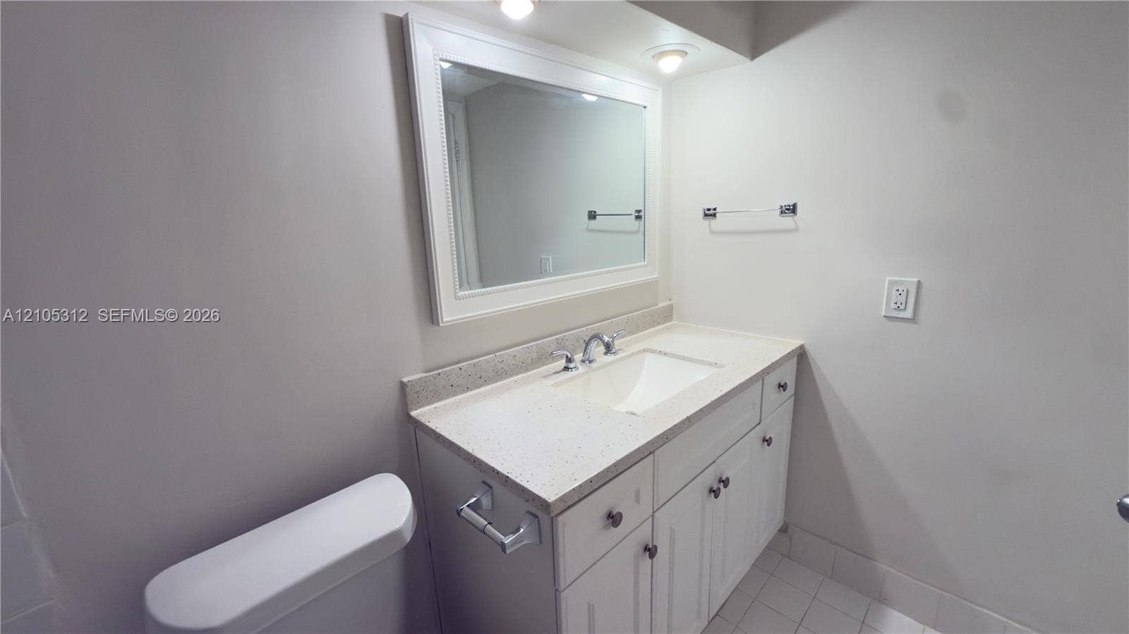 6900 N Kendall Drive, #A304, Pinecrest, Pinecrest, FL 33156 White vanity with stone-composite countertop and integrated sink, framed wall mirror, recessed lighting, and tile flooring