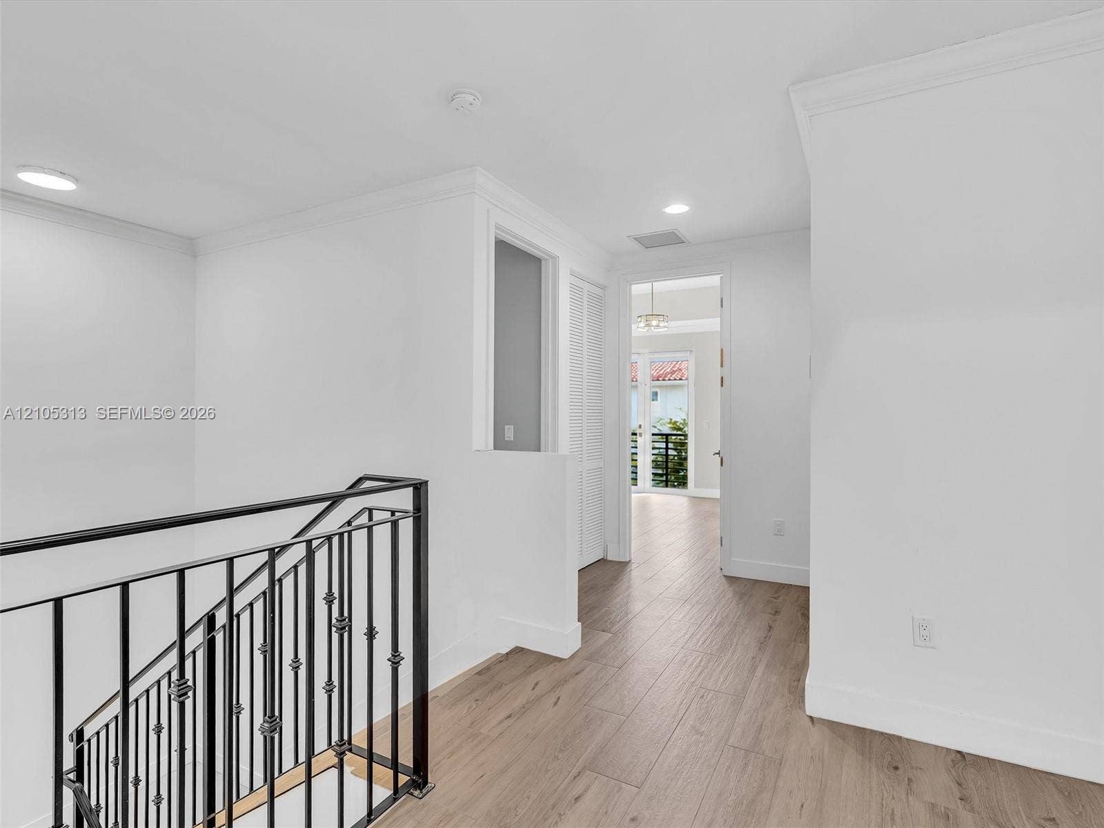 Interior space featuring wood-finish flooring, metal staircase railing, crown molding, and recessed lighting