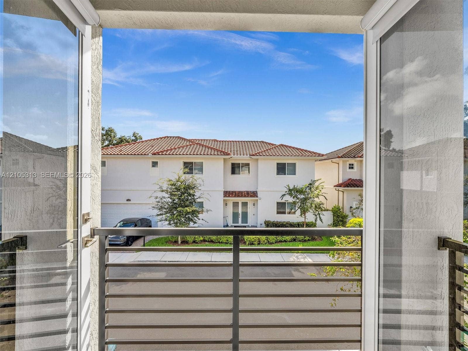 Balcony featuring a metal horizontal-slat railing, glass-panel exterior door, and stucco finish