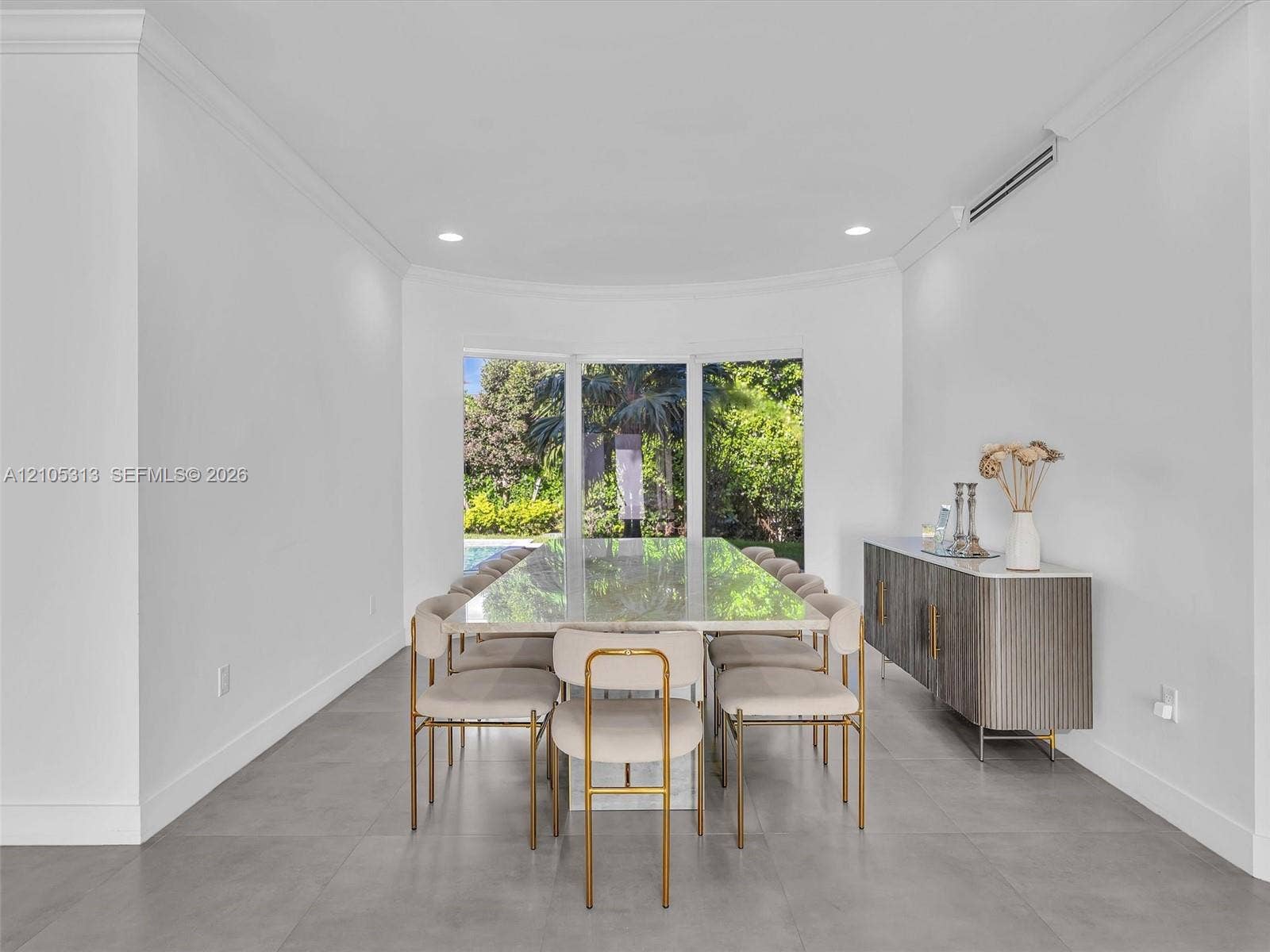 Curved wall alcove featuring floor-to-ceiling windows and large-format tile flooring with crown molding and recessed lighting