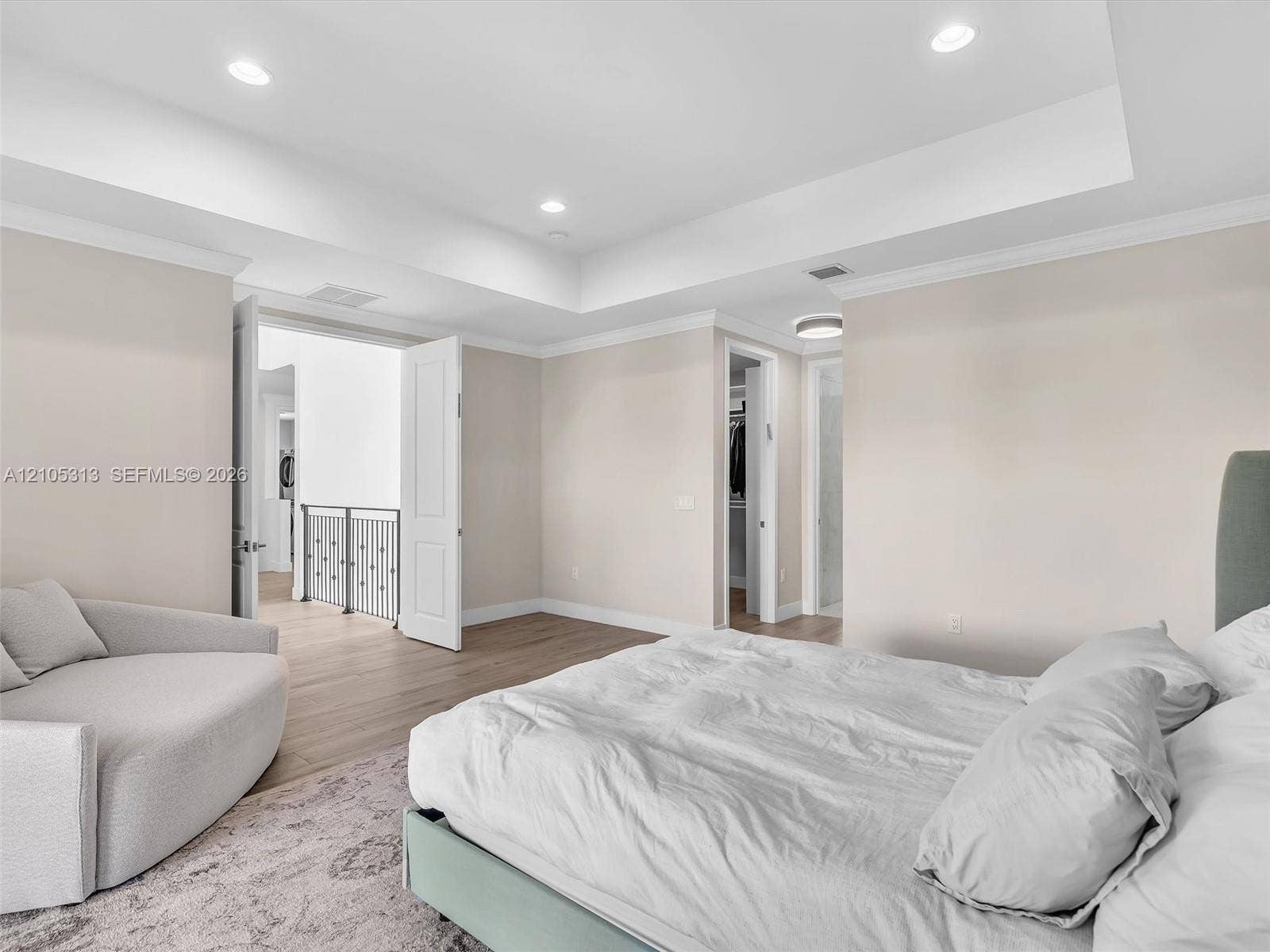 Tray ceiling with recessed lighting, wood-finish flooring, and crown molding