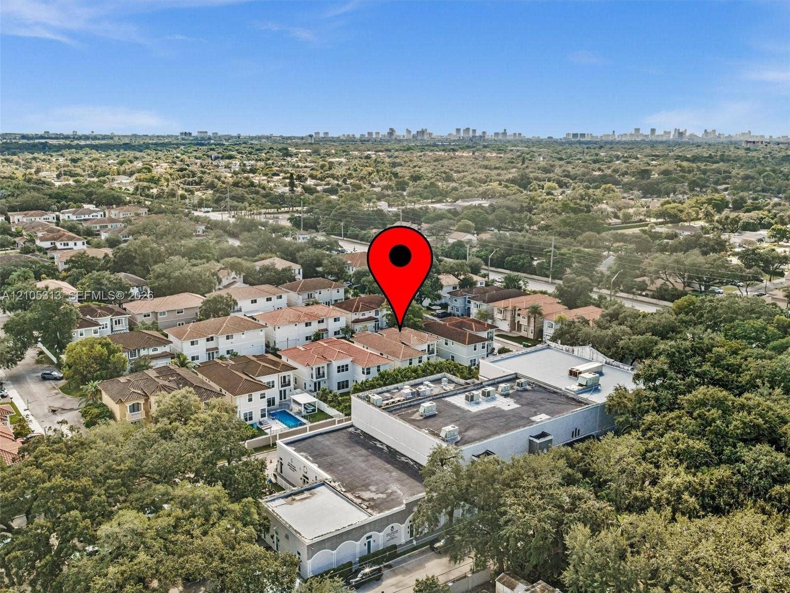 Aerial perspective of residential area featuring multi-level structures, tile roofing, and expansive tree canopy coverage