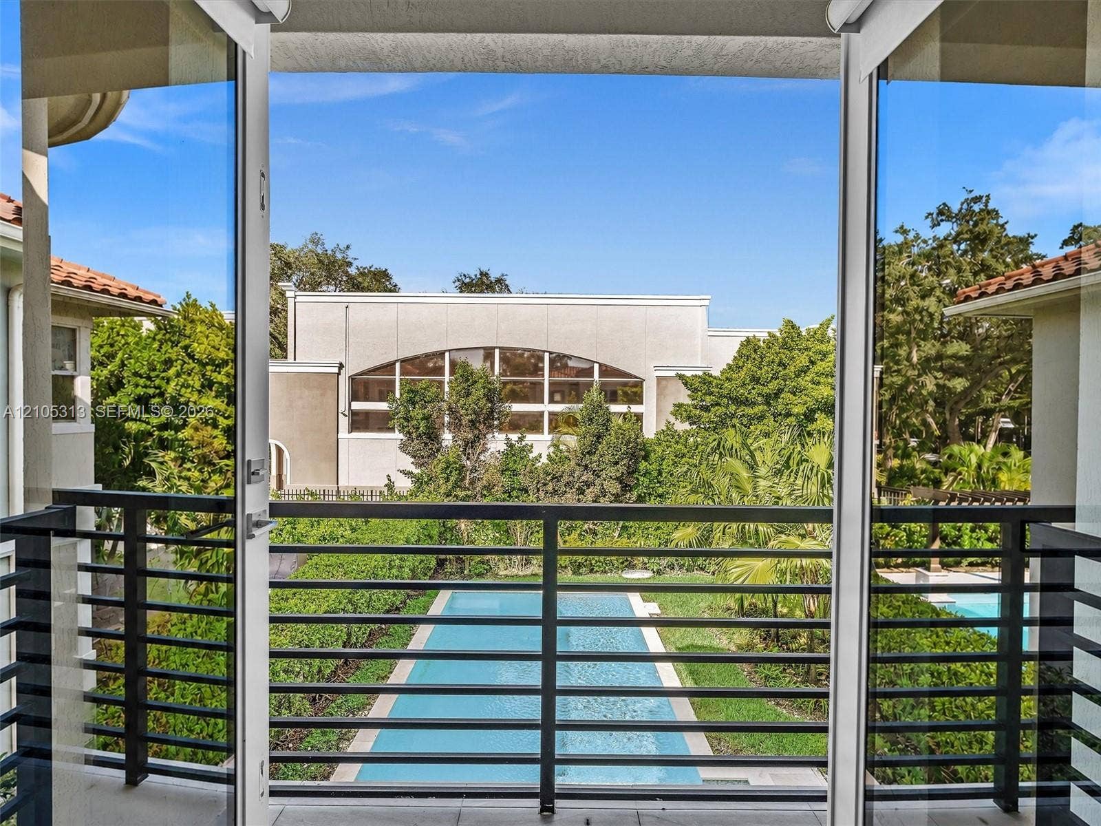 Covered balcony featuring black metal railings, double-glass entry doors, and a rectangular in-ground swimming pool