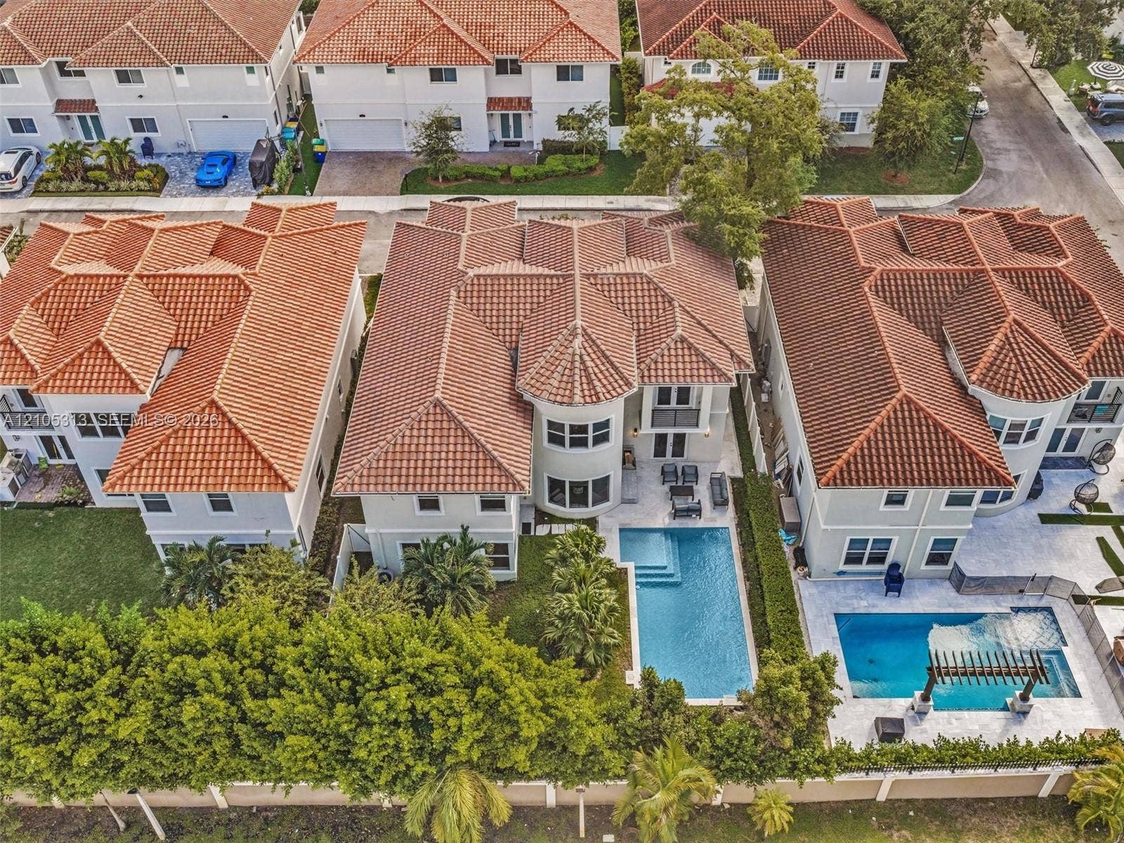 Multi-story residential property featuring a tiled roof, stucco exterior, private swimming pool, and stone-surfaced patio area