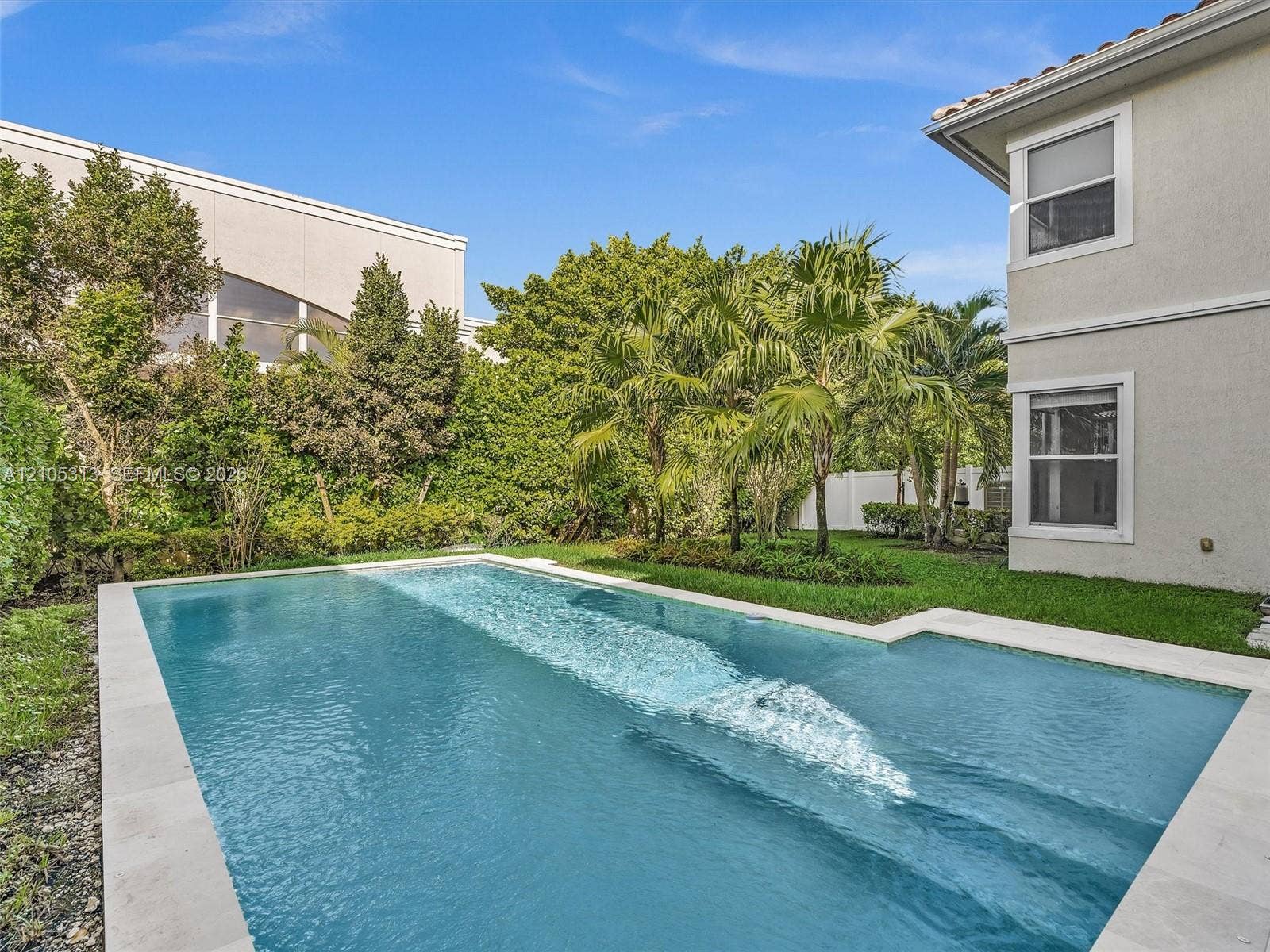 Private backyard featuring an in-ground swimming pool with a stone paver surround, manicured lawn, and mature perimeter landscaping