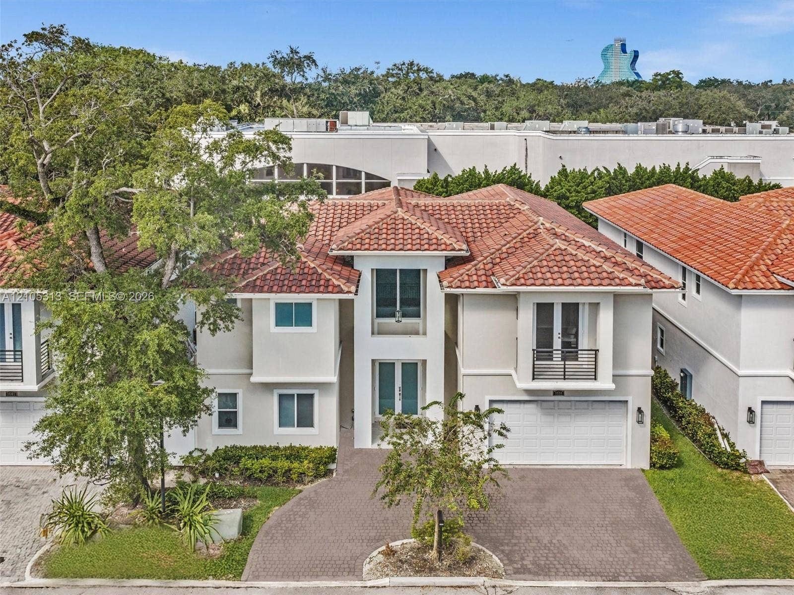 Two-story residence featuring a Mediterranean-style tile roof, stucco exterior, paved driveway, two-car garage, and a second-story balcony with metal railing
