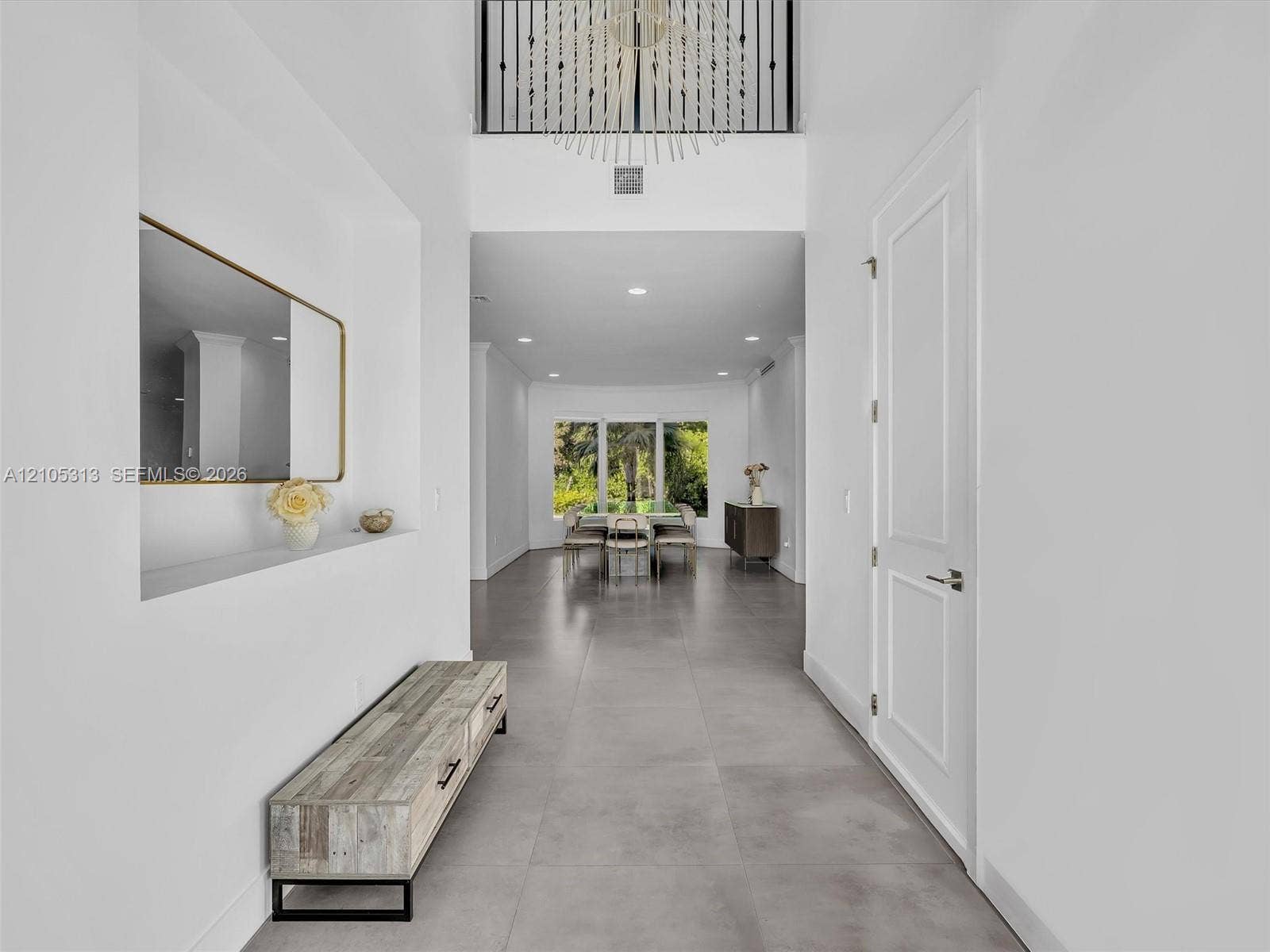 Foyer featuring a double-height ceiling, large-format tile flooring, a recessed wall niche, and an elevated chandelier with wrought-iron detailing