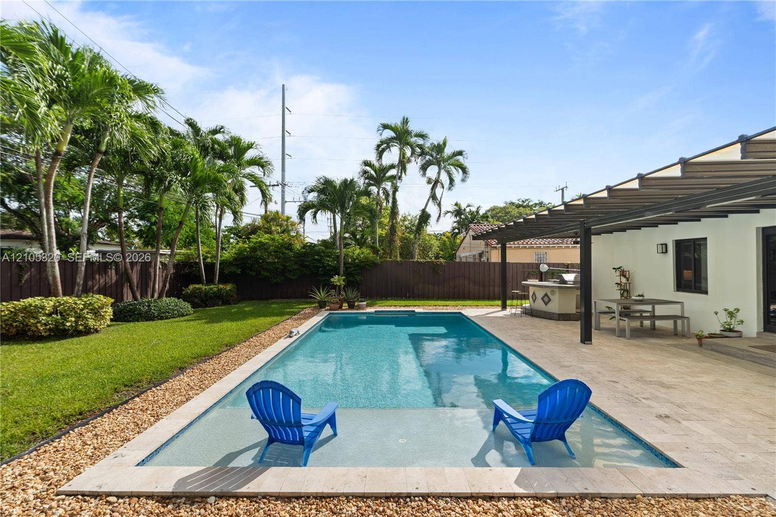 Rectangular swimming pool with a sun shelf, surrounded by a paved patio and lush green lawn