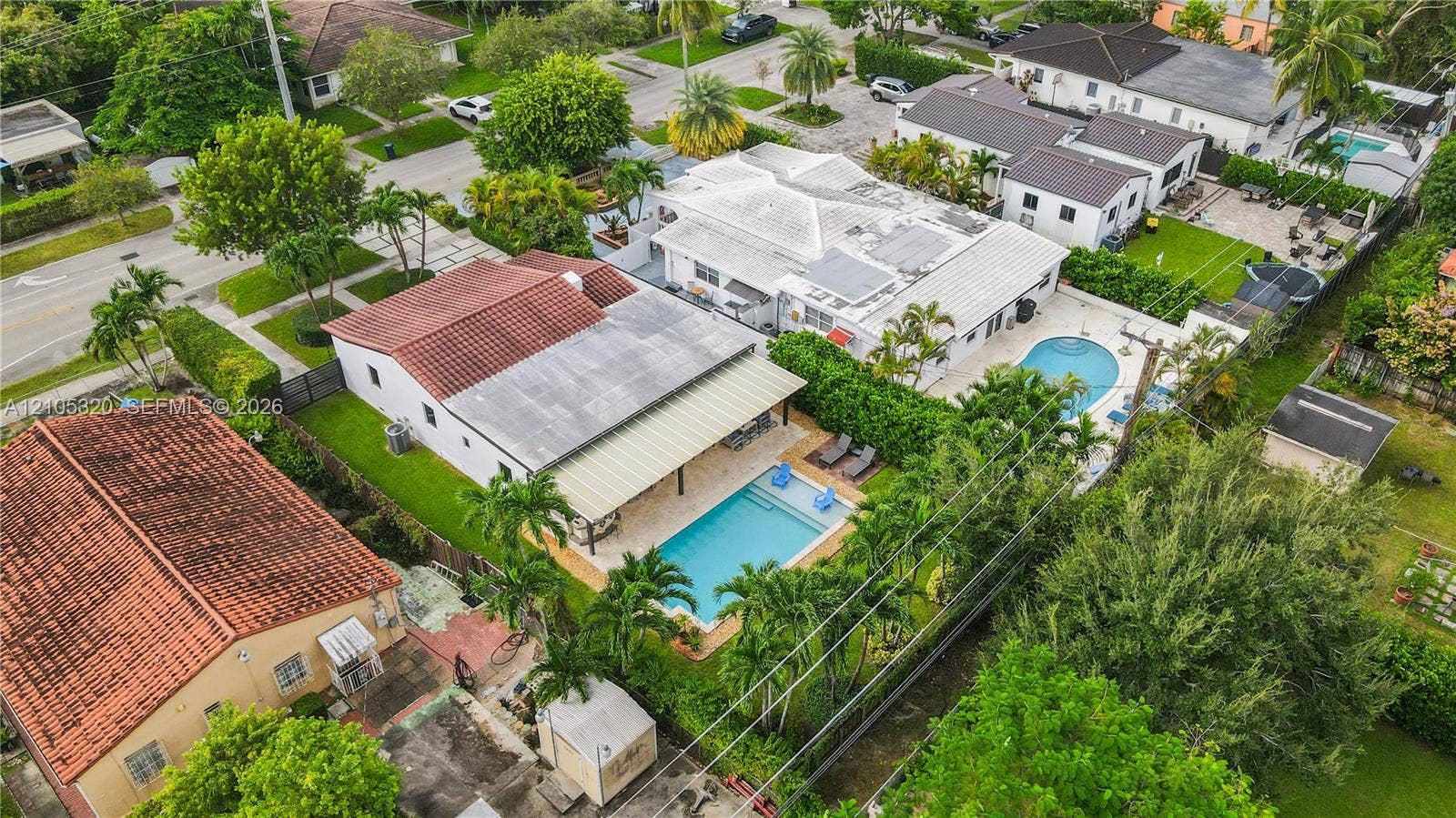 Expansive property featuring two distinct swimming pools, mature landscaping, and an attached covered patio