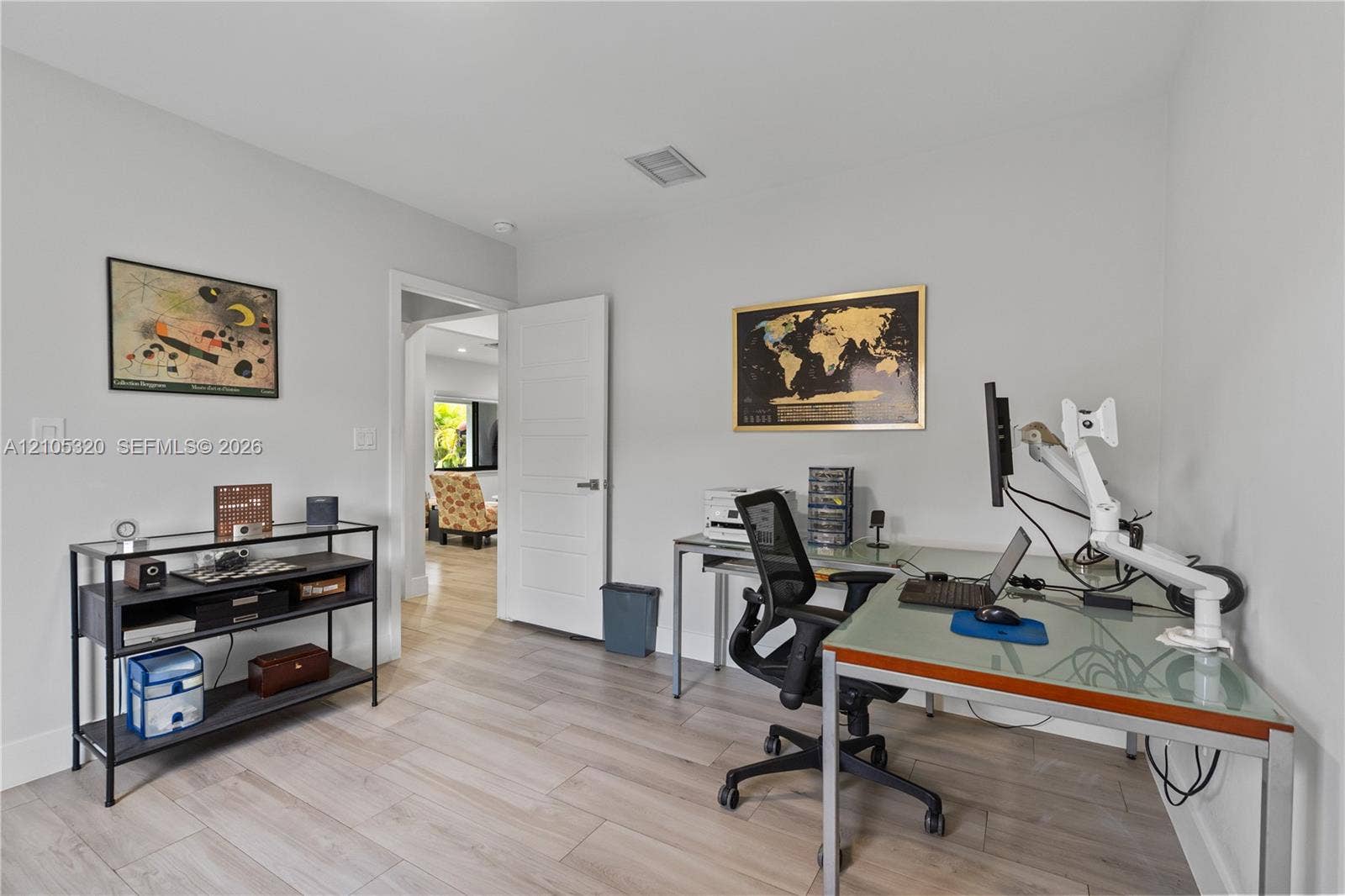 Light-toned wood-finish flooring, white walls, recessed ceiling lighting, and a modern interior door