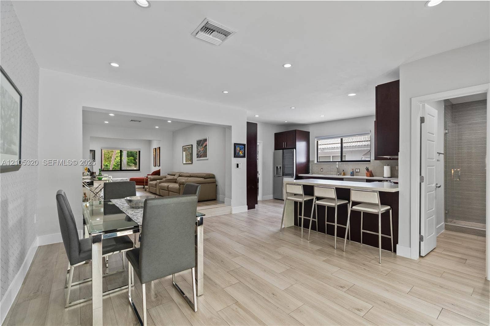 Light wood-finish flooring, recessed lighting, and a kitchen island with seating