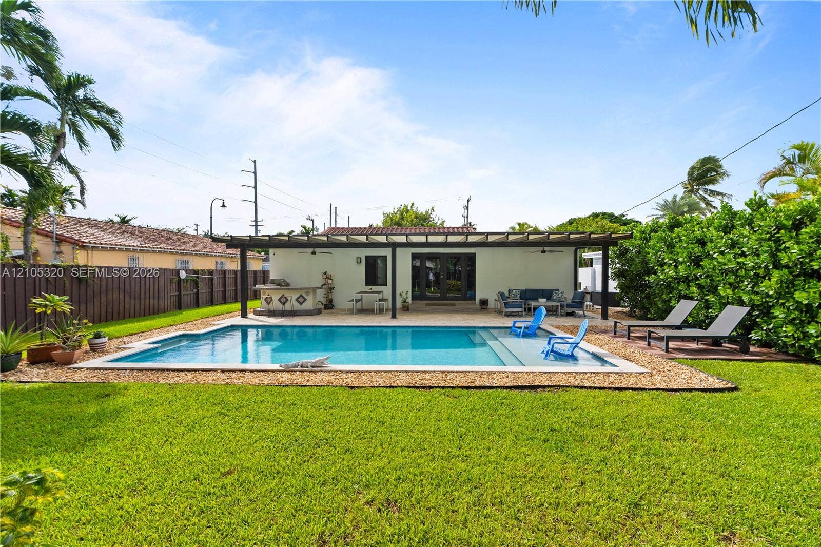Rectangular swimming pool with, gravel surround, and a stucco exterior house