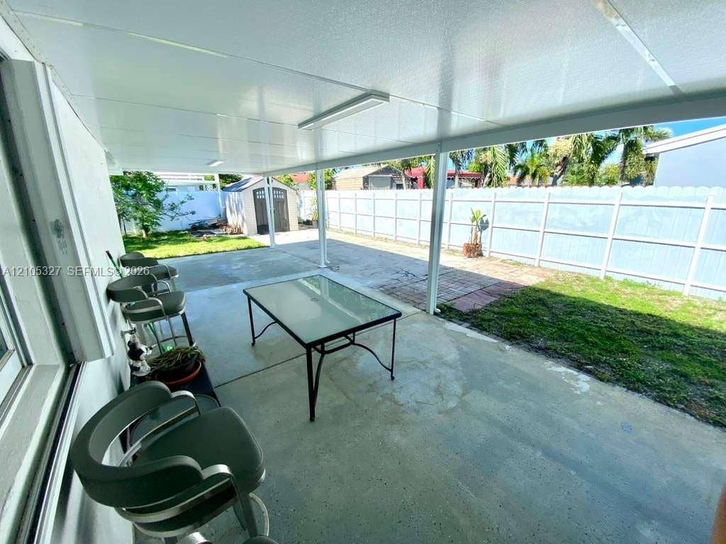 Covered patio with concrete flooring, fenced backyard, and a storage shed