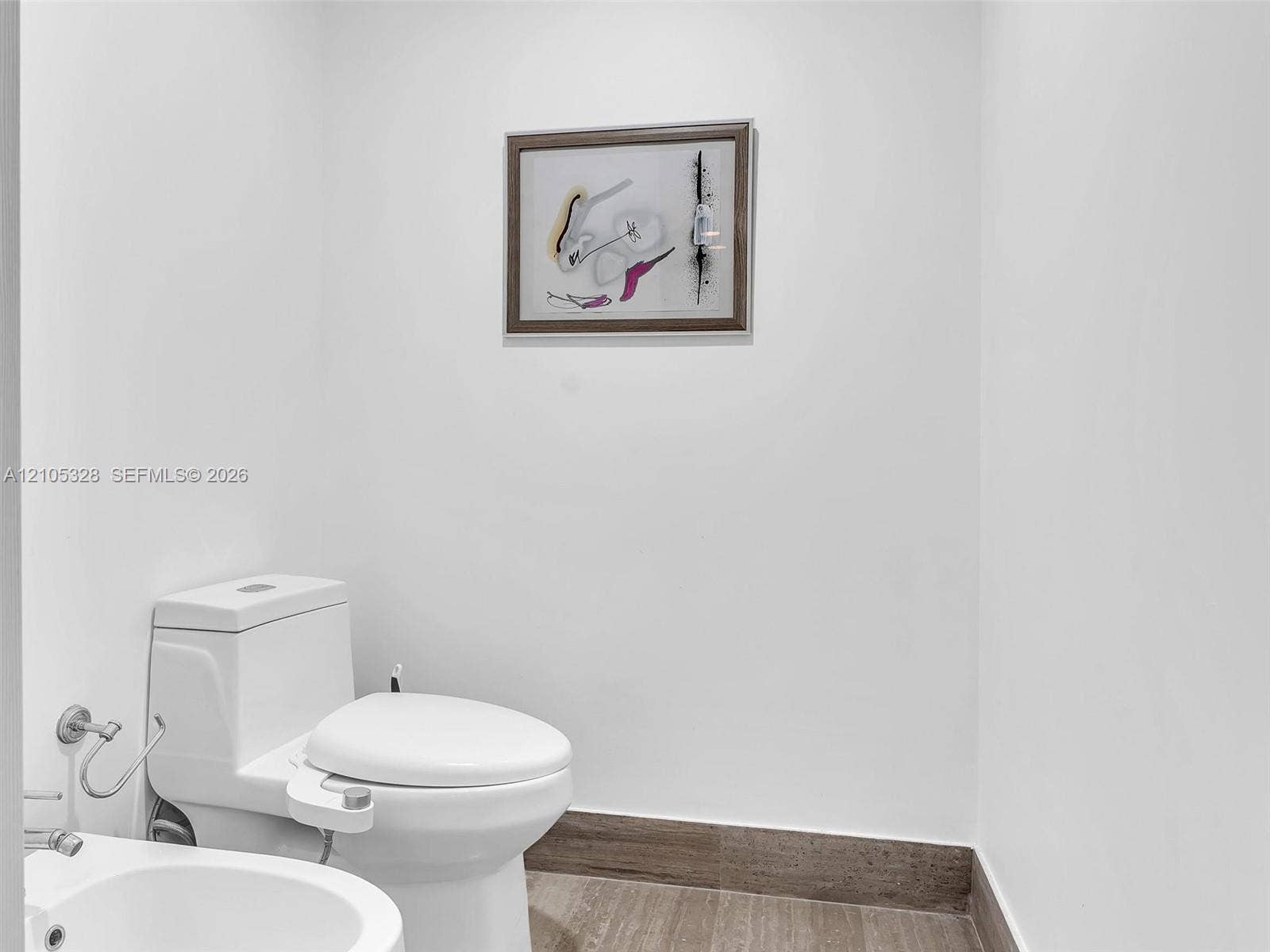 3951 S Ocean Drive, #1901, Hollywood, FL 33019 Elegantly appointed private bathroom featuring crisp white walls, warm wood-look flooring, and a modern toilet with an integrated bidet.