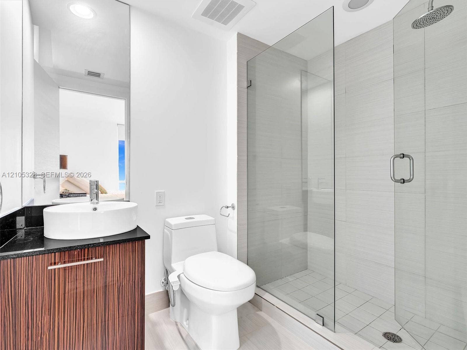 3951 S Ocean Drive, #1901, Hollywood, FL 33019 Elegant contemporary bathroom featuring a sleek vanity with warm finish cabinetry and a sophisticated dark countertop.