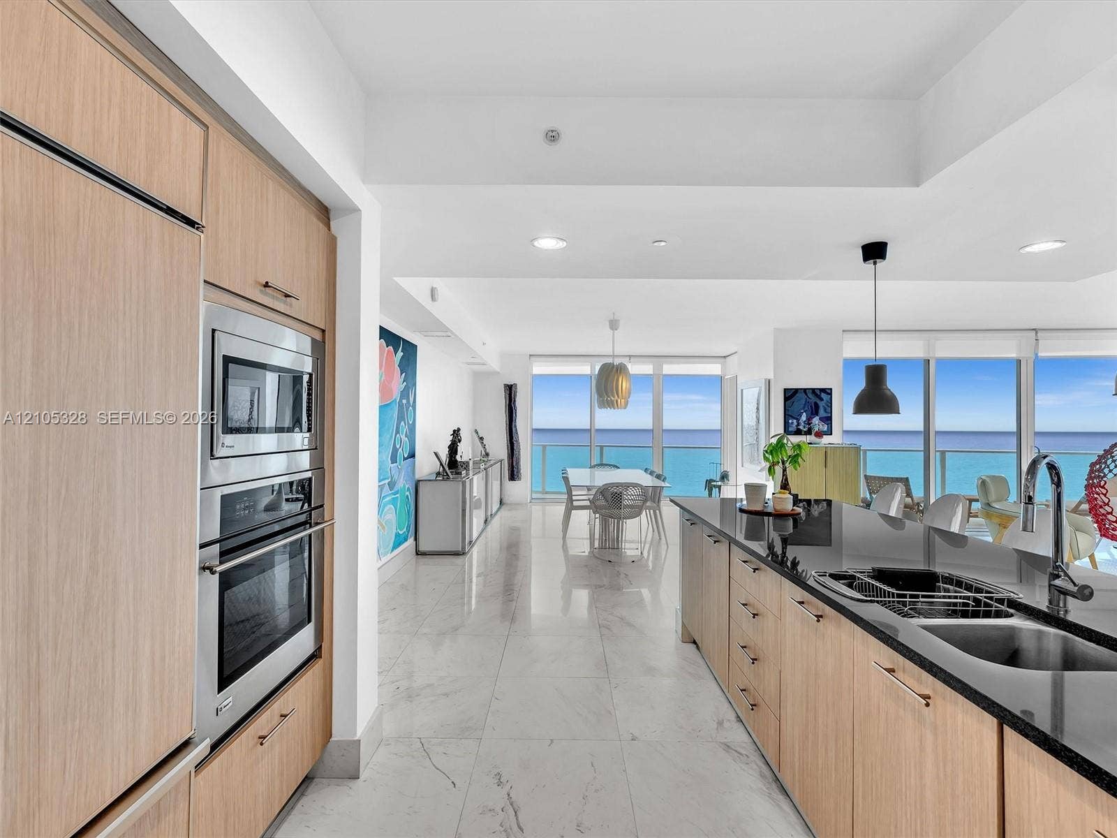 3951 S Ocean Drive, #1901, Hollywood, FL 33019 Gourmet kitchen featuring wood-finish cabinetry, stainless steel appliances, and sleek dark stone countertops with an undermount sink.