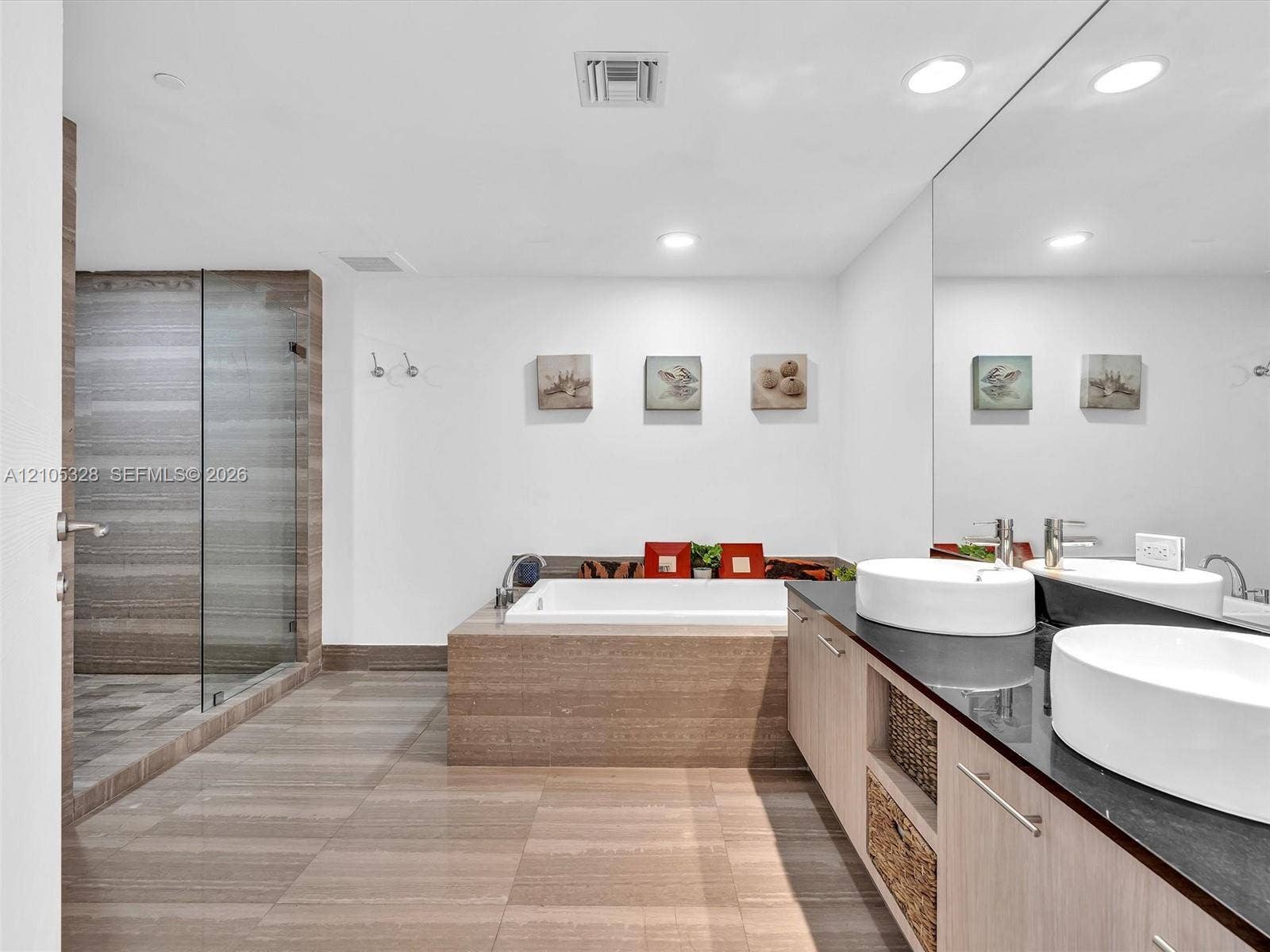 3951 S Ocean Drive, #1901, Hollywood, FL 33019 Luxurious spa-inspired bathroom featuring dual vessel sinks, an expansive vanity with built-in storage, a full-width mirror, a soaking tub, and a separate glass-enclosed shower.