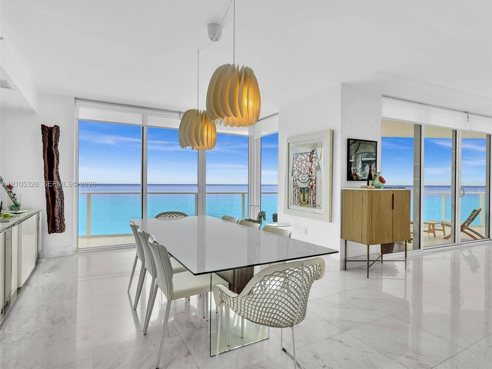3951 S Ocean Drive, #1901, Hollywood, FL 33019 Elegant dining area featuring floor-to-ceiling glass doors and windows, large-format tile flooring, contemporary pendant lighting, and a glass-top dining table.