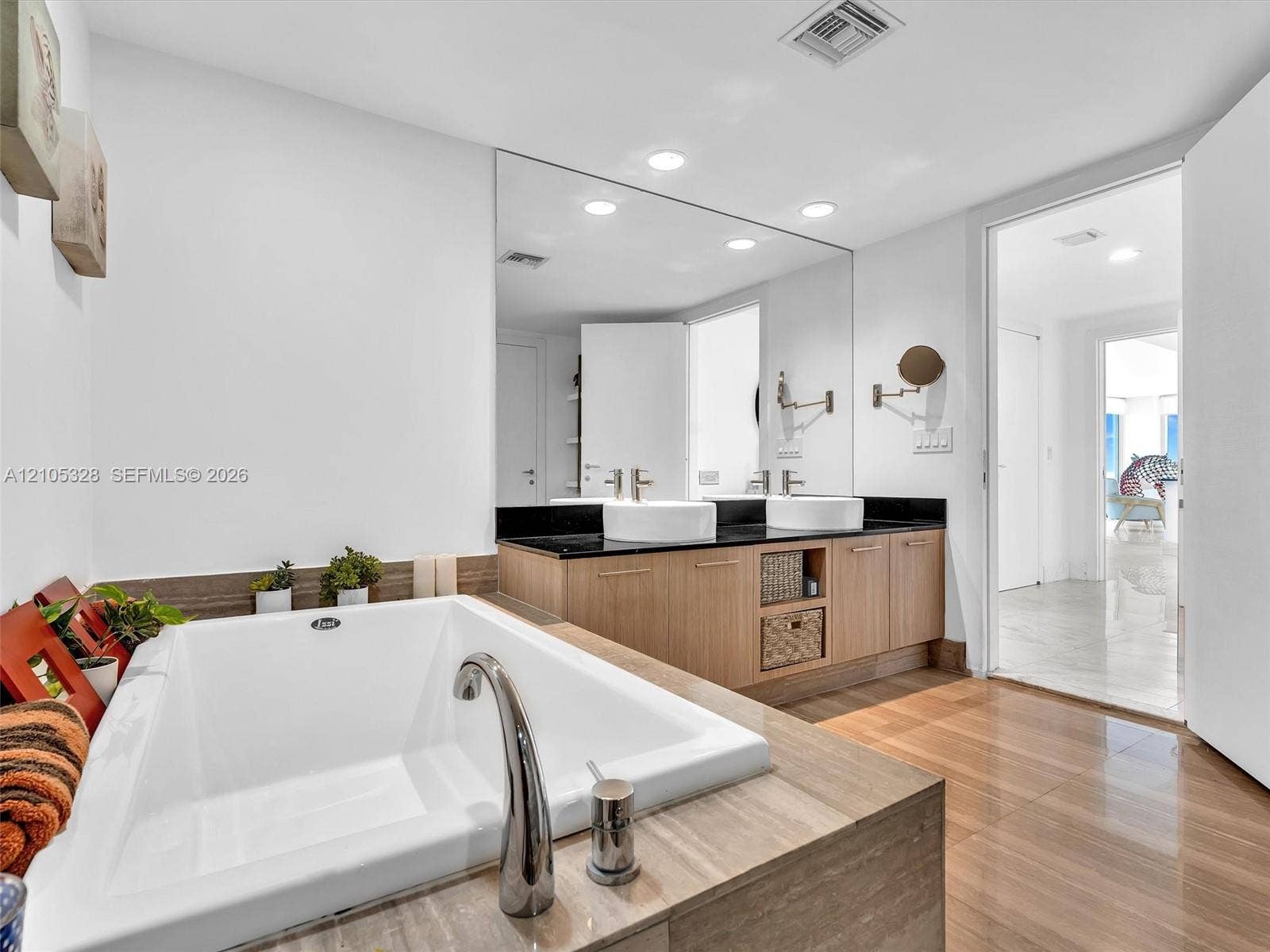 3951 S Ocean Drive, #1901, Hollywood, FL 33019 Luxurious spa-inspired bathroom featuring dual vessel sinks, an expansive vanity with built-in storage, a full-width mirror, a soaking tub, and a separate glass-enclosed shower.