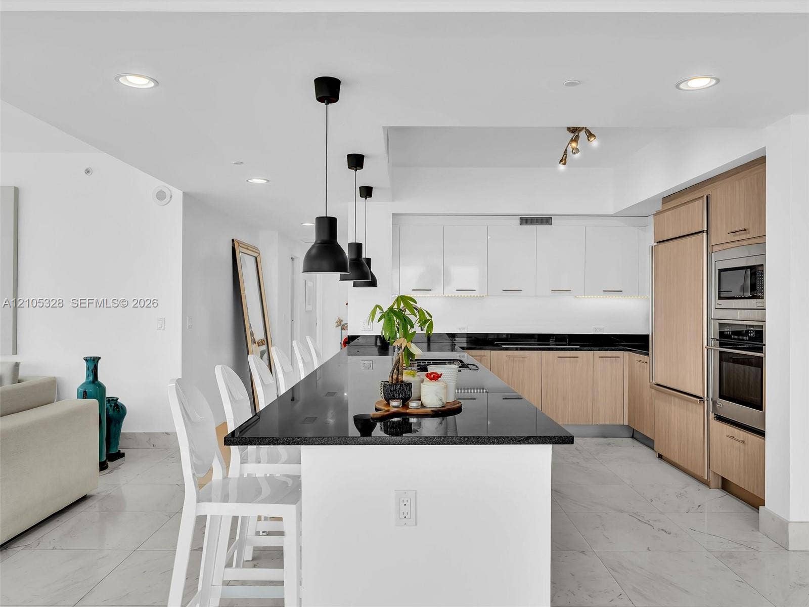 3951 S Ocean Drive, #1901, Hollywood, FL 33019 Modern gourmet kitchen featuring an oversized center island with seating, sleek dark stone countertops, stainless steel appliances, and wood-finish cabinetry.