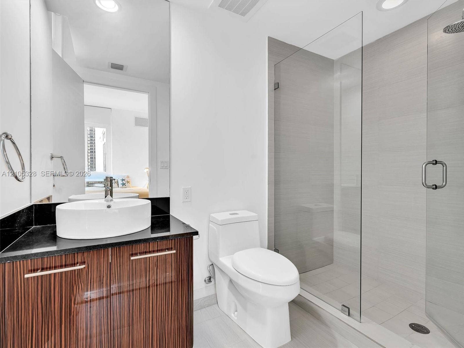 3951 S Ocean Drive, #1901, Hollywood, FL 33019 Elegant contemporary bathroom featuring a sleek vanity with warm finish cabinetry and a sophisticated dark countertop.