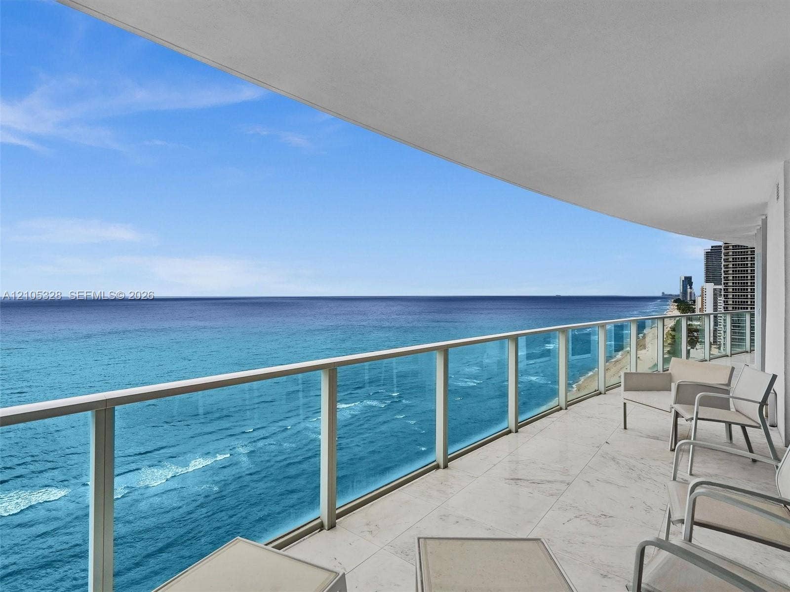 3951 S Ocean Drive, #1901, Hollywood, FL 33019 Expansive private balcony featuring glass railings, stone tile flooring, and unobstructed ocean views.