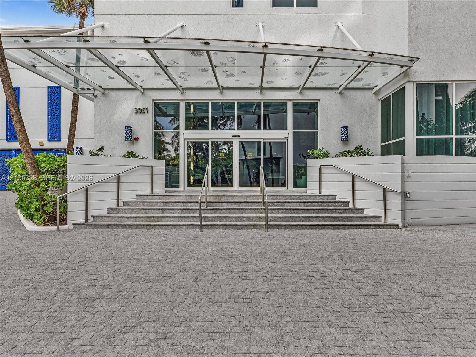 3951 S Ocean Drive, #1901, Hollywood, FL 33019 Elegant building entrance featuring a contemporary glass canopy, beautifully paved entryway, and sleek stainless steel railings, creating a sophisticated arrival experience.