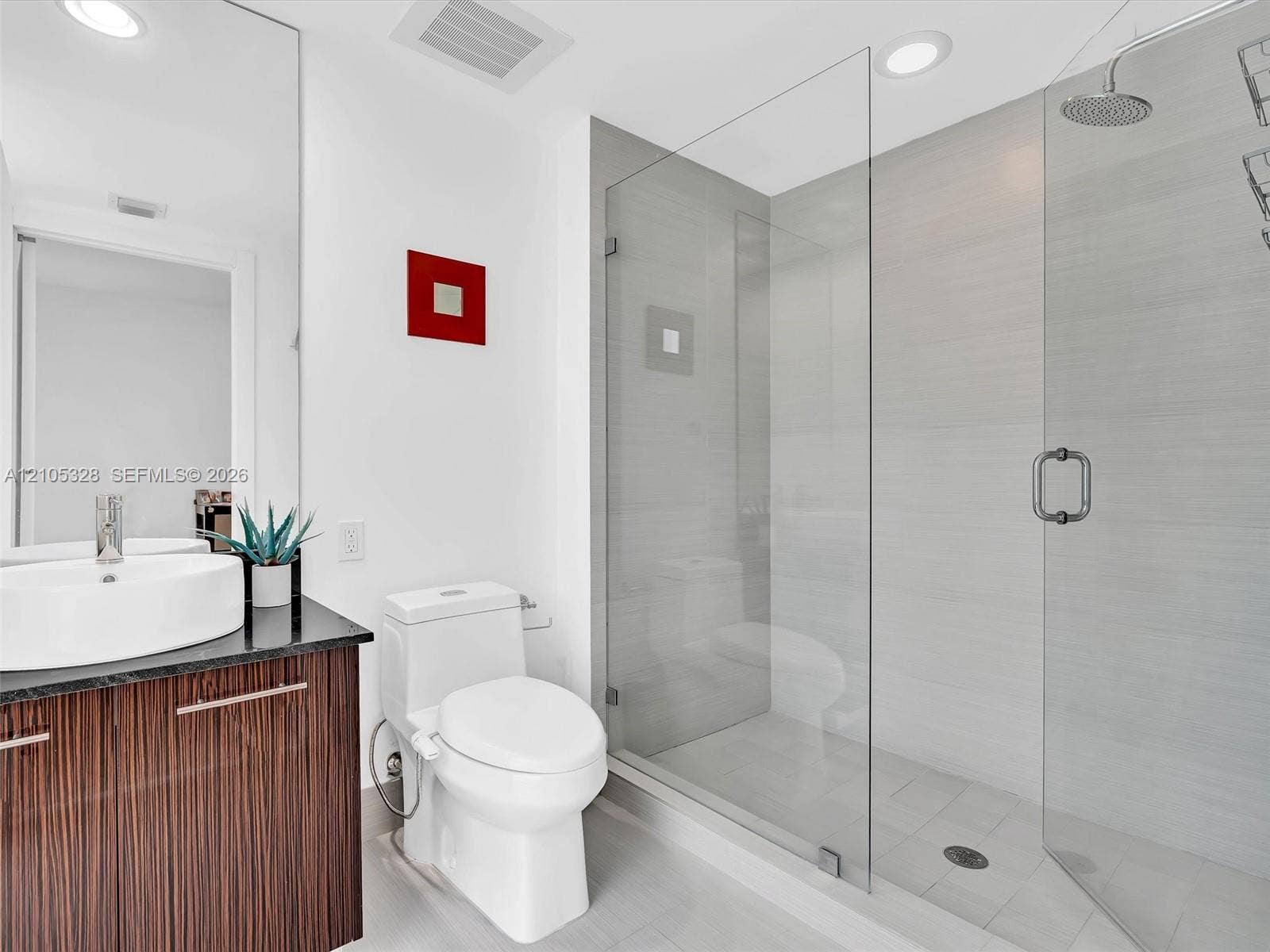3951 S Ocean Drive, #1901, Hollywood, FL 33019 Elegant contemporary bathroom featuring a sleek vanity with warm finish cabinetry and a sophisticated dark countertop.
