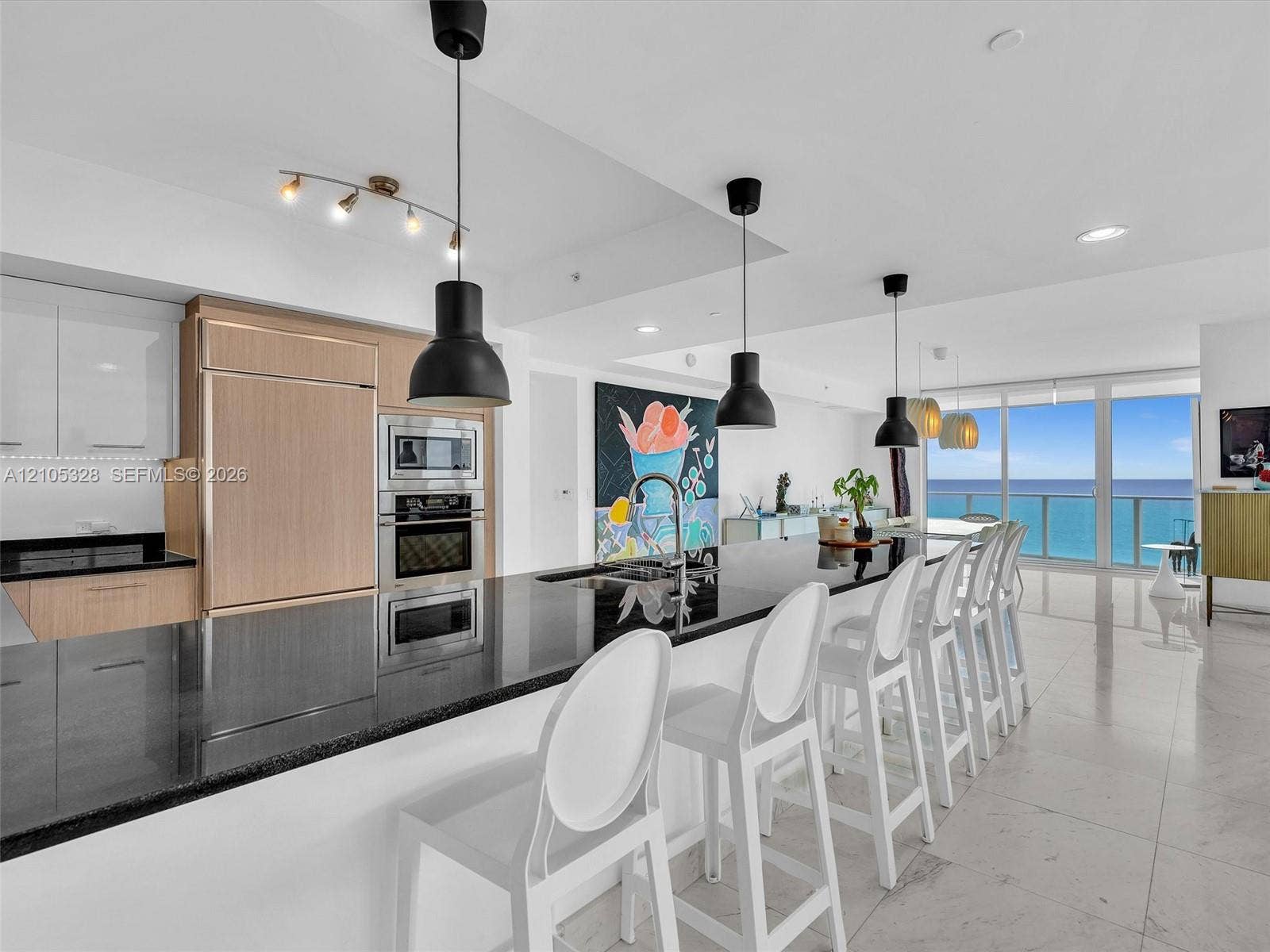 3951 S Ocean Drive, #1901, Hollywood, FL 33019 Gourmet kitchen featuring integrated appliances, sleek black countertops, and contemporary pendant lighting.