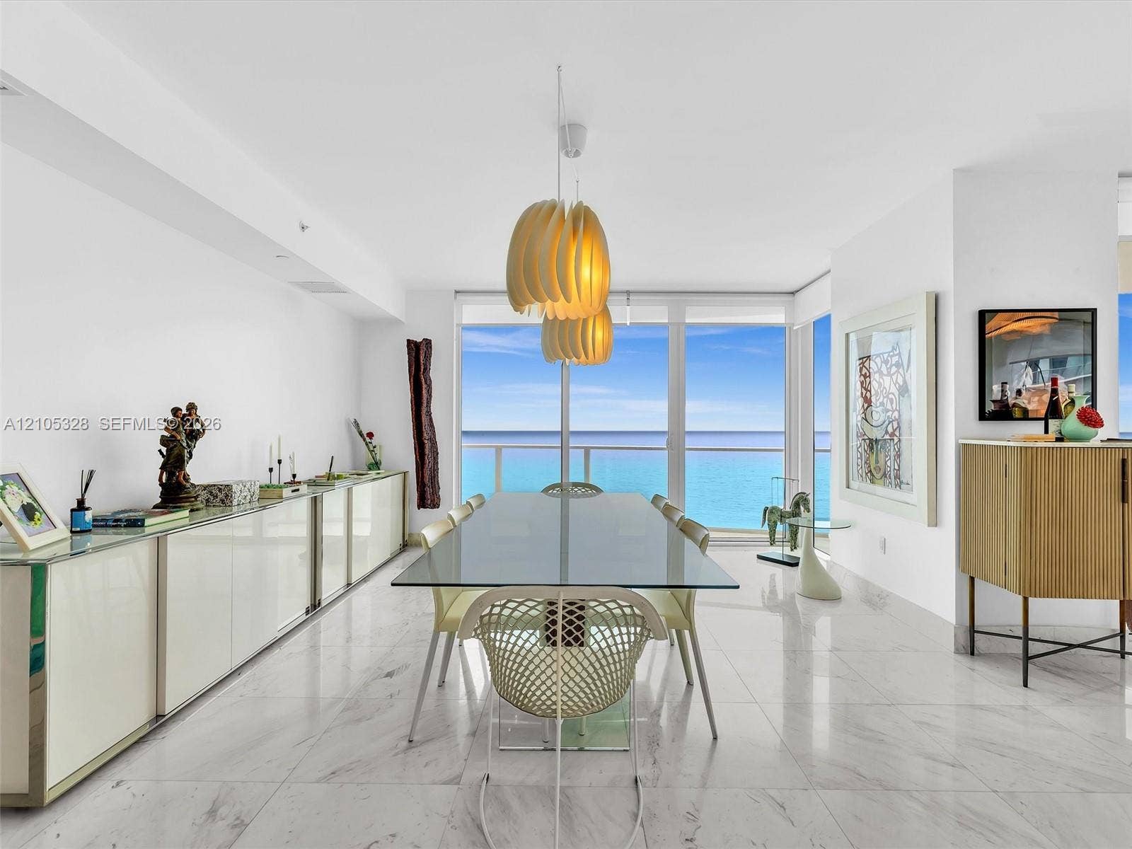 3951 S Ocean Drive, #1901, Hollywood, FL 33019 Elegant dining area featuring floor-to-ceiling glass doors and windows, large-format tile flooring, contemporary pendant lighting, and a glass-top dining table.