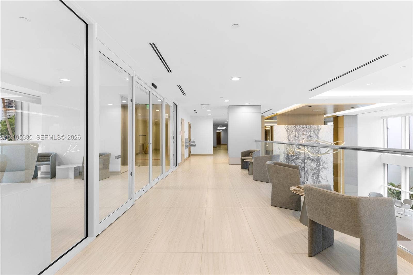 21205 Yacht Club Drive, #304, Aventura, FL 33180 Expansive hallway with light-toned tiled flooring, floor-to-ceiling glass paneling, recessed lighting, and a glass-paneled railing with a metal top rail