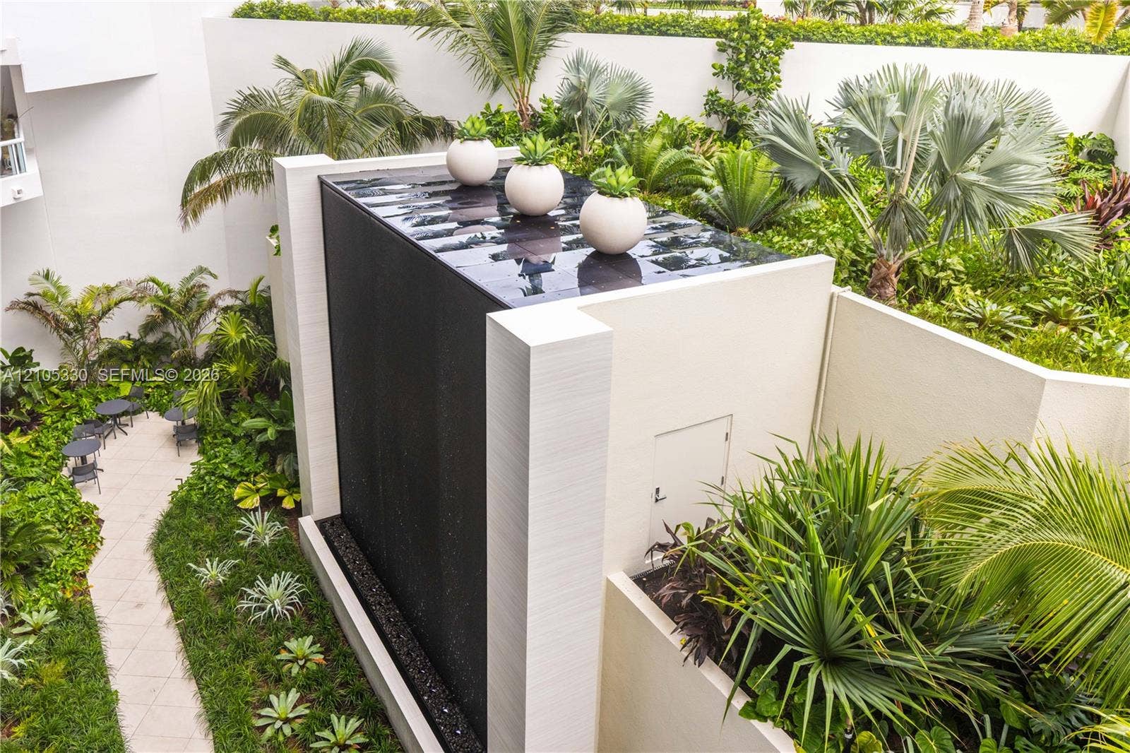 21205 Yacht Club Drive, #304, Aventura, FL 33180 Modern water feature with a black finish, lush tropical landscaping, and a paver pathway
