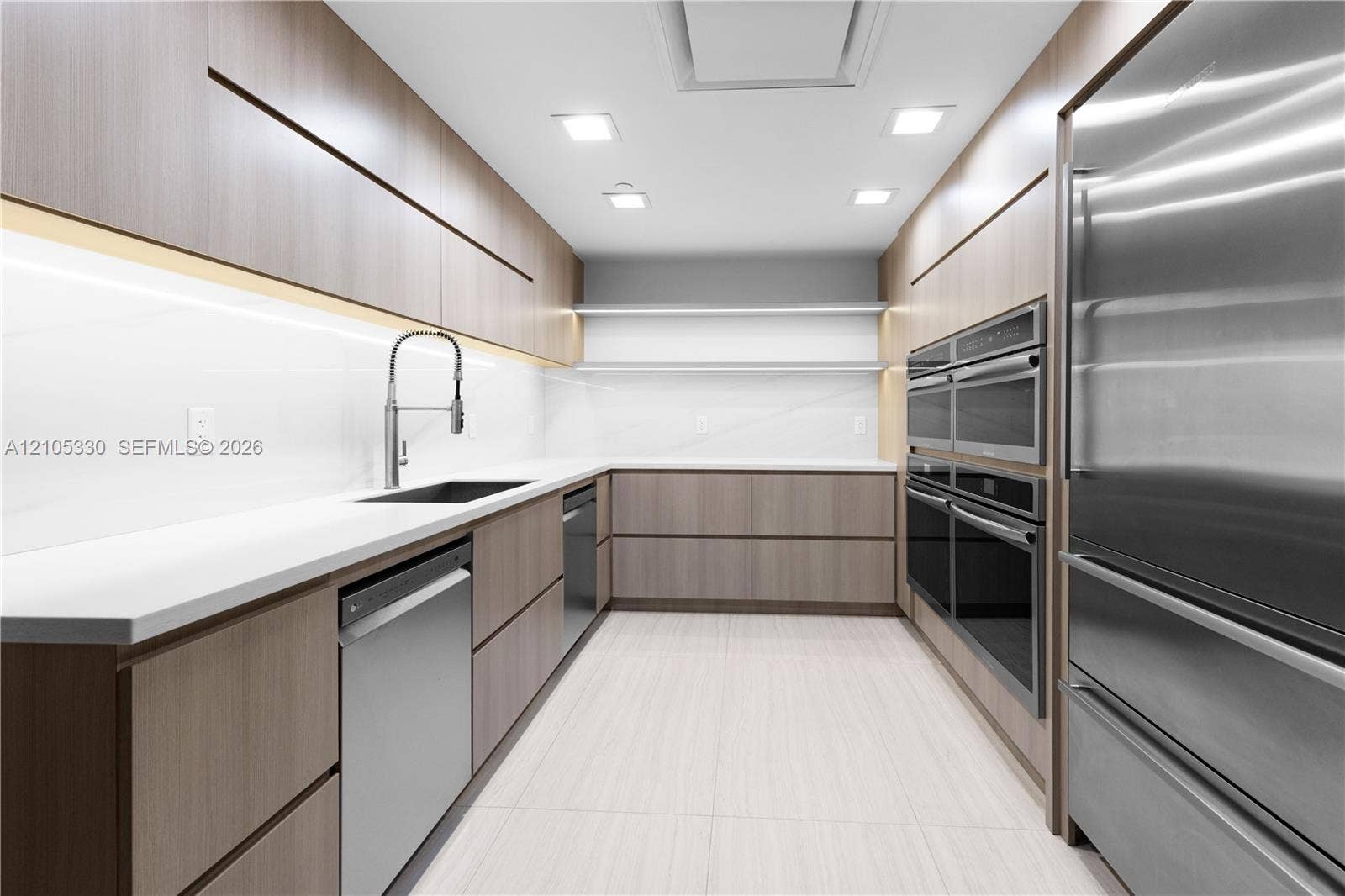 21205 Yacht Club Drive, #304, Aventura, FL 33180 Modern kitchen featuring light wood-finish cabinetry, white countertops, integrated stainless steel appliances, and recessed ceiling lighting