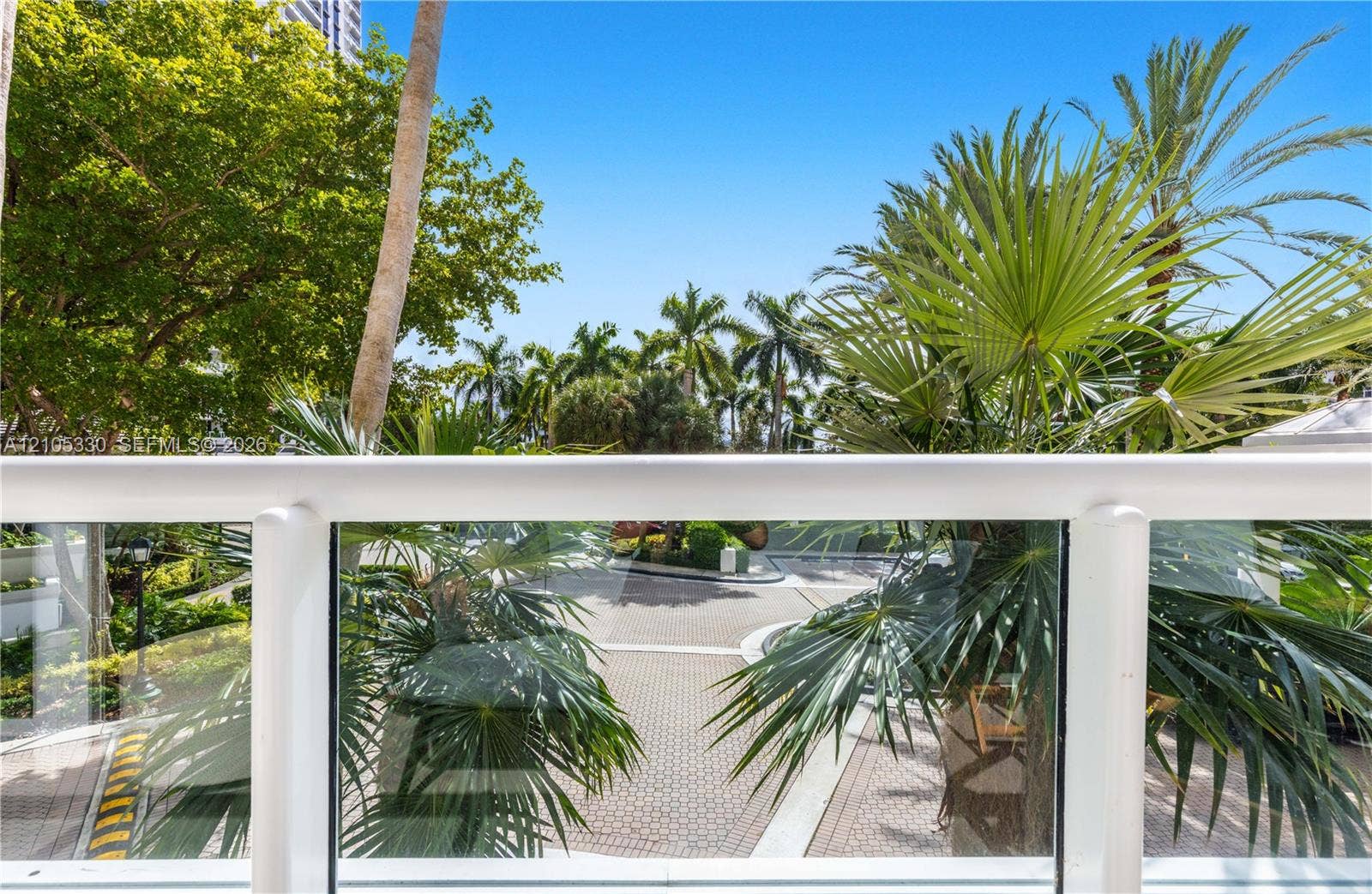 21205 Yacht Club Drive, #304, Aventura, FL 33180 Balcony with glass railing overlooking mature palm trees and lush landscaping