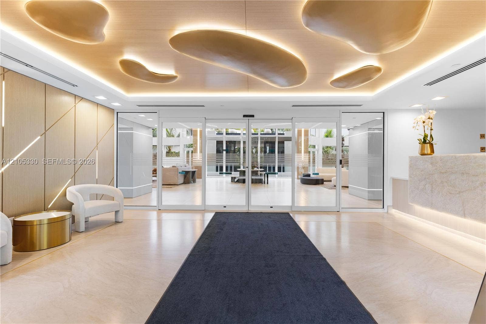 21205 Yacht Club Drive, #304, Aventura, FL 33180 Lobby featuring a stone reception desk, wood-panel accent wall, recessed ceiling lighting, and large glass entry doors