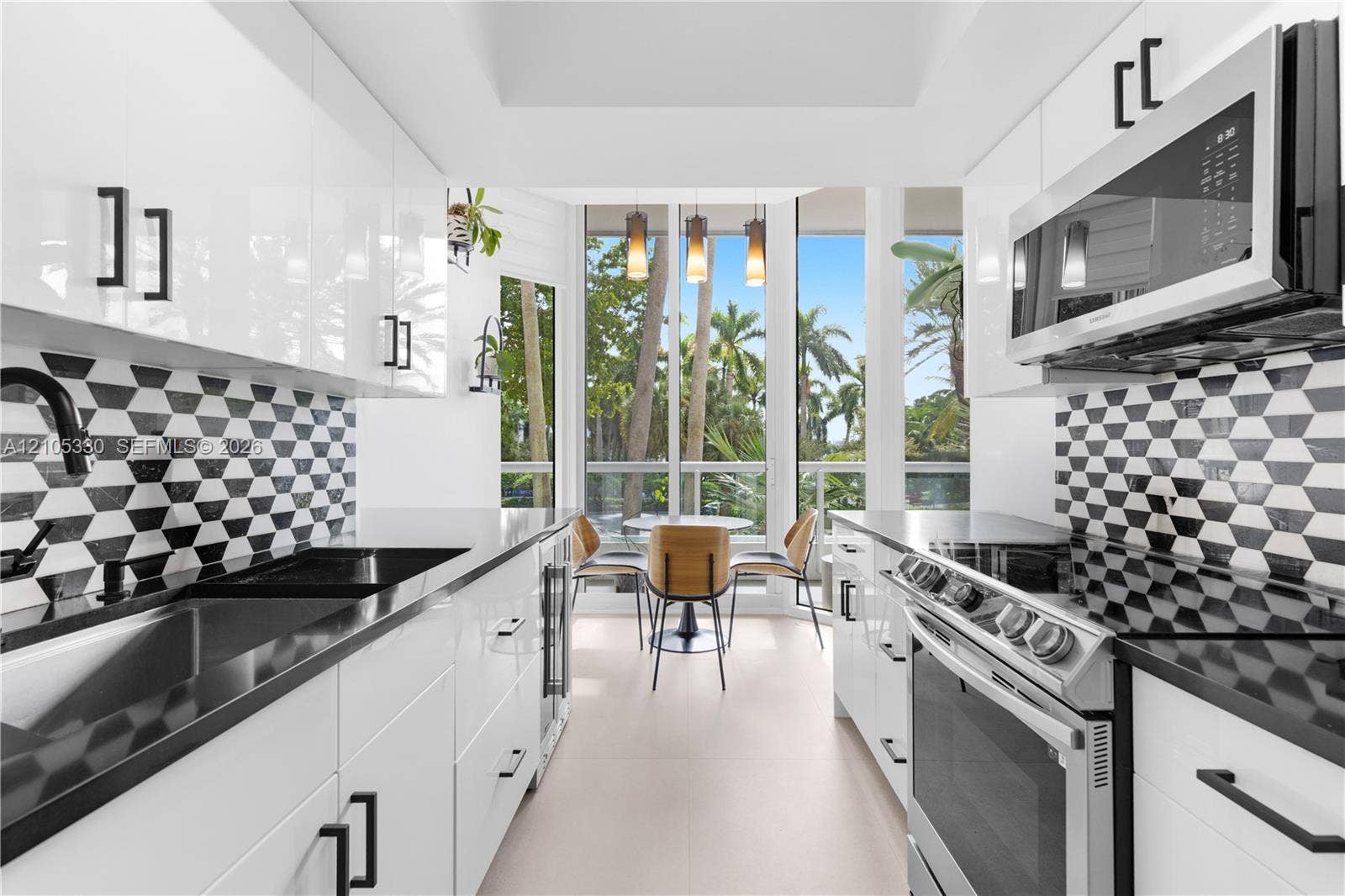 21205 Yacht Club Drive, #304, Aventura, FL 33180 Contemporary kitchen featuring white high-gloss cabinetry, black hardware, black countertops, and a striking geometric tile backsplash