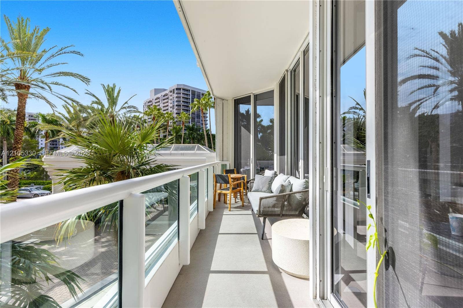 21205 Yacht Club Drive, #304, Aventura, FL 33180 Expansive balcony featuring a glass and white railing, concrete flooring, and full-height sliding glass doors