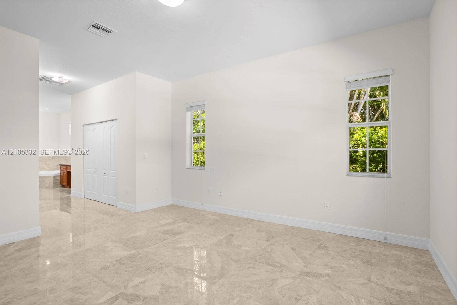 Polished tile flooring, two windows with roller shades, recessed lighting, and bifold closet doors