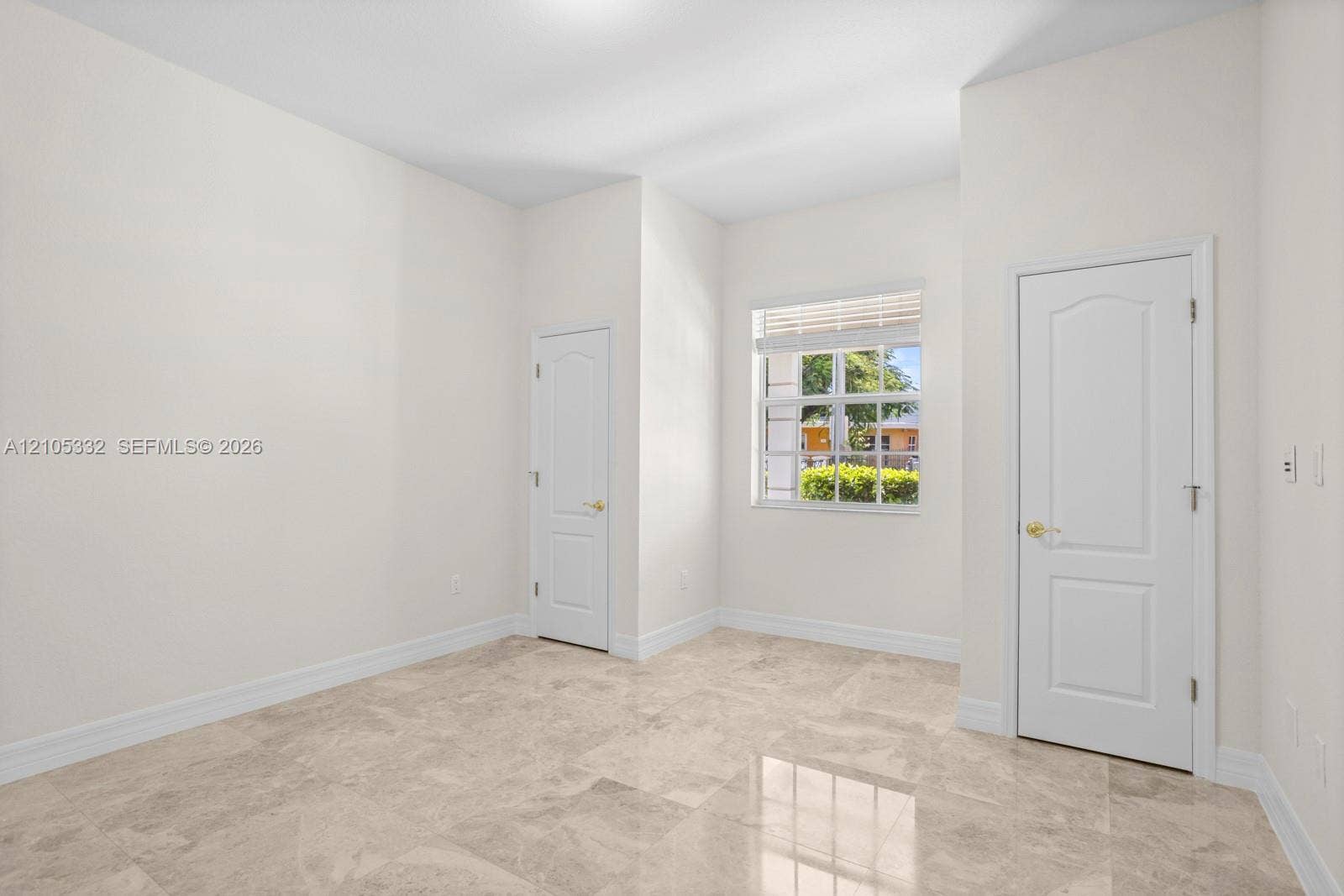 Neutral-toned tile flooring, white interior walls, white two-panel interior doors, and a window with horizontal blinds