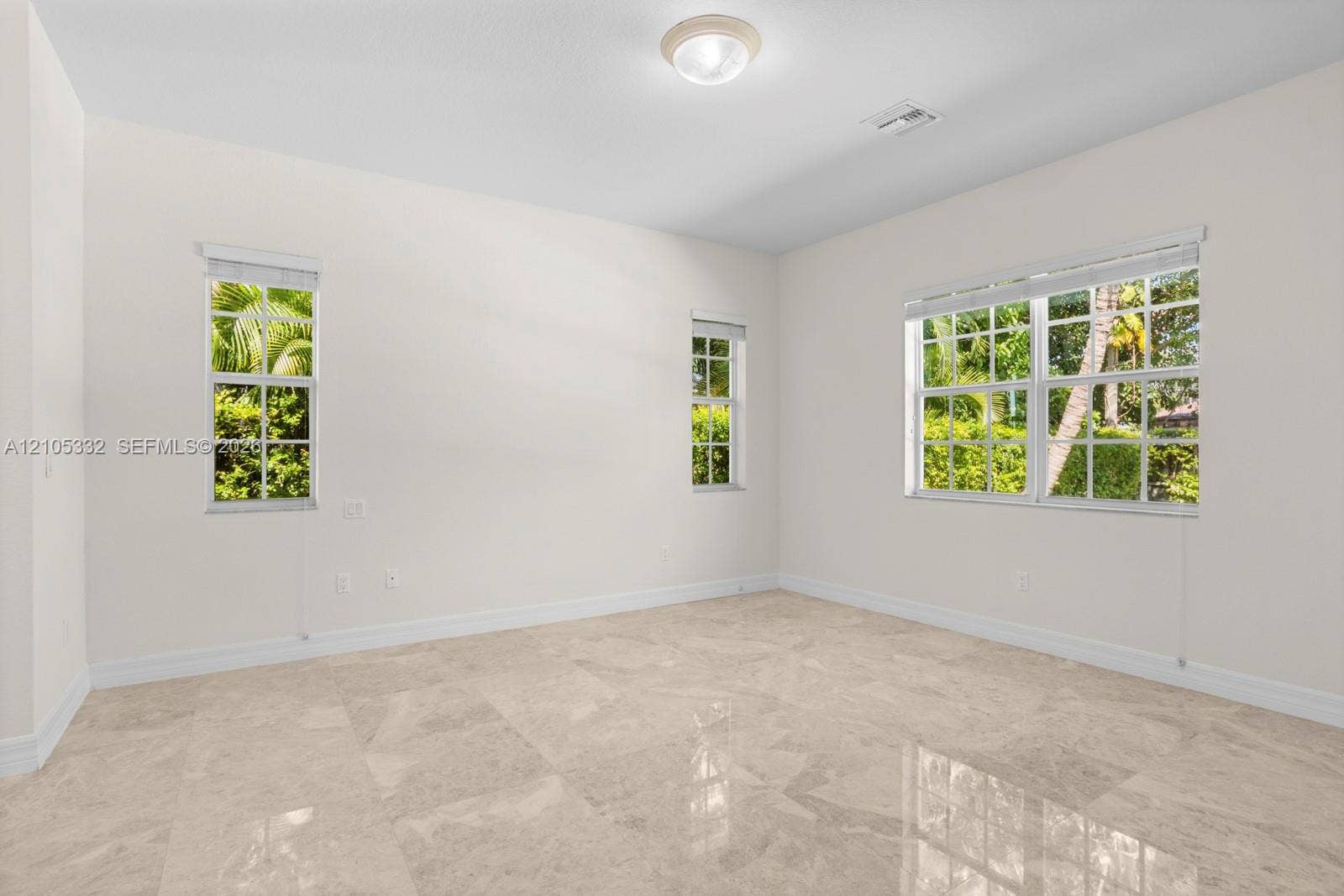 Polished tile flooring, multiple windows, overhead flush-mount lighting, and neutral wall tones