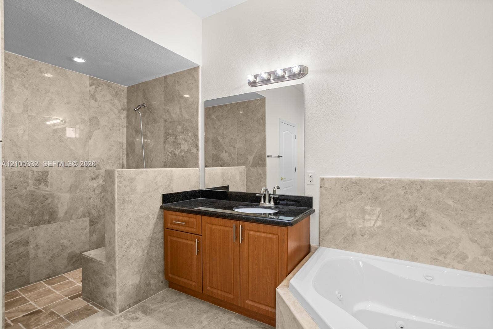 Walk-in shower with tiled walls and floor, built-in bench, and handheld showerhead